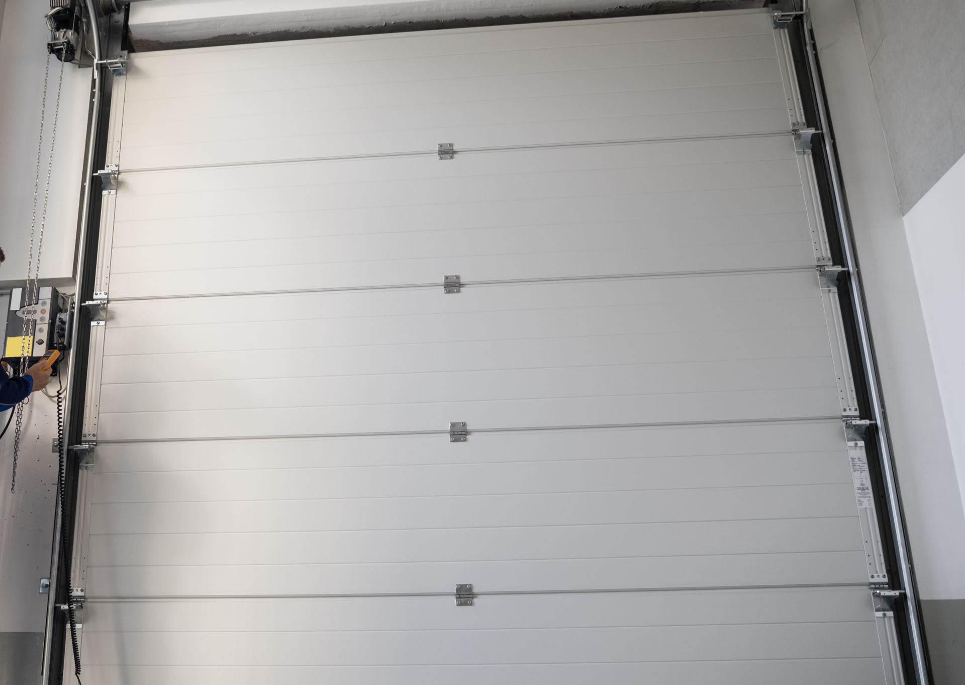 A man is working on a garage door in a garage.
