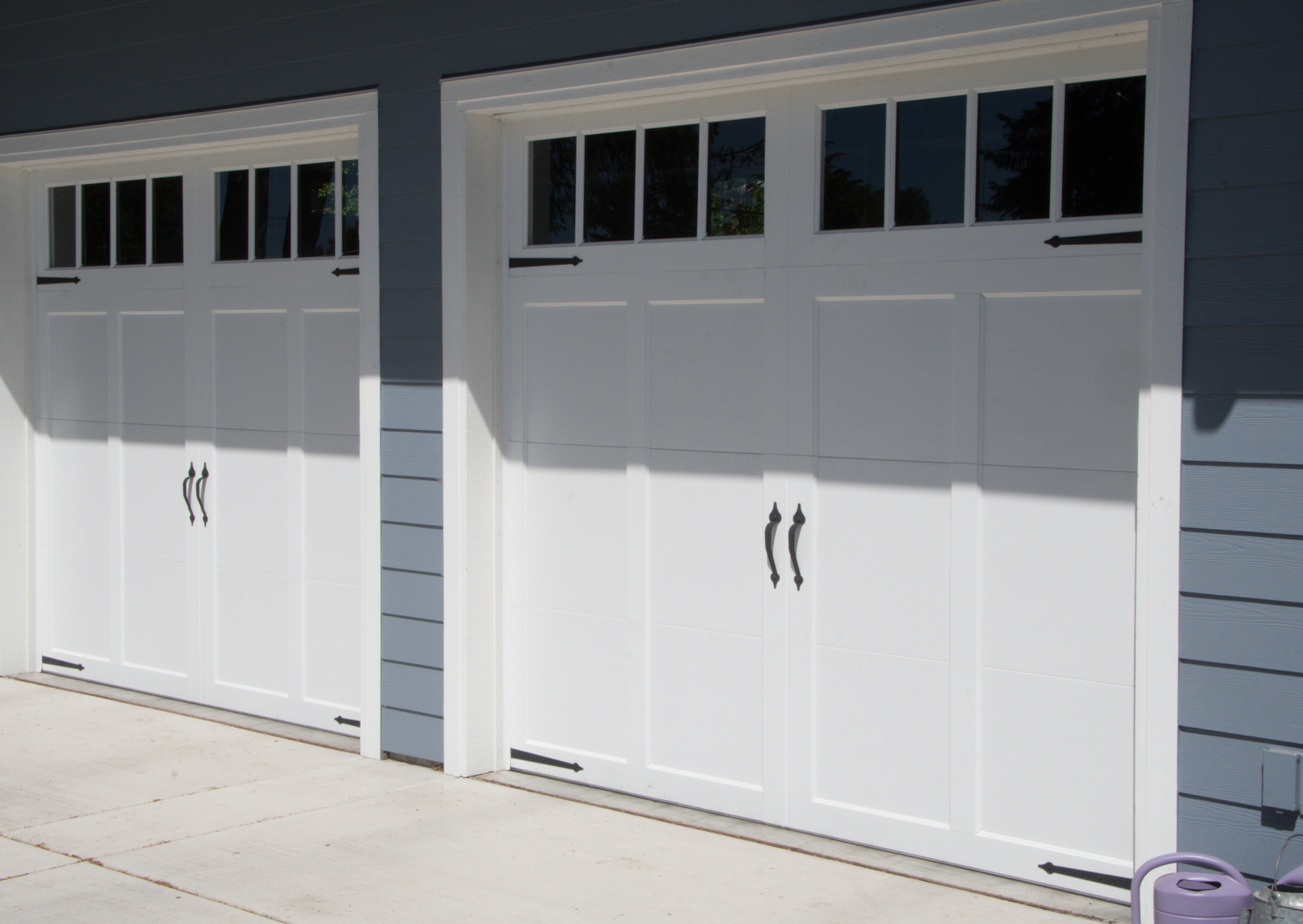 A couple of white garage doors on a blue house