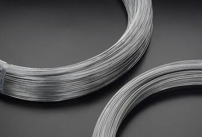 Fasci di filo color argento arrotolati su uno sfondo grigio.