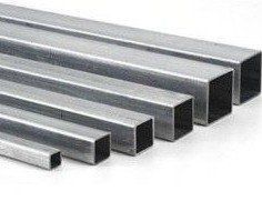 Tubi quadrati in acciaio di varie dimensioni, impilati, che riflettono la luce.