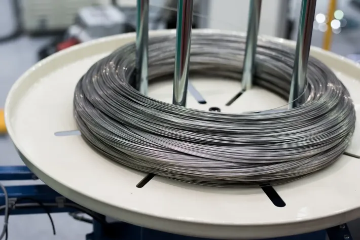 Bobina di filo metallico, avvolta strettamente su una piattaforma circolare bianca.