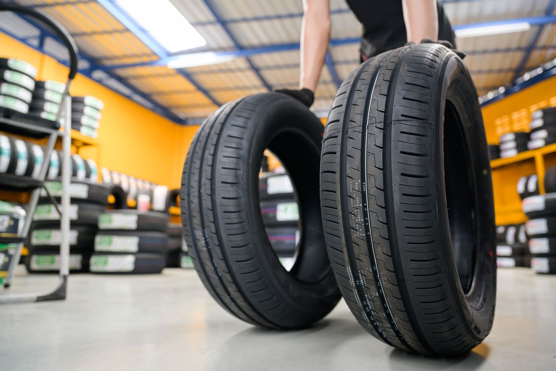 Two New Black Car Tires Standing in a Tire Shop, With a Person Blurred in the Background — Mareeba Tyre Centre in Mareeba, QLD
