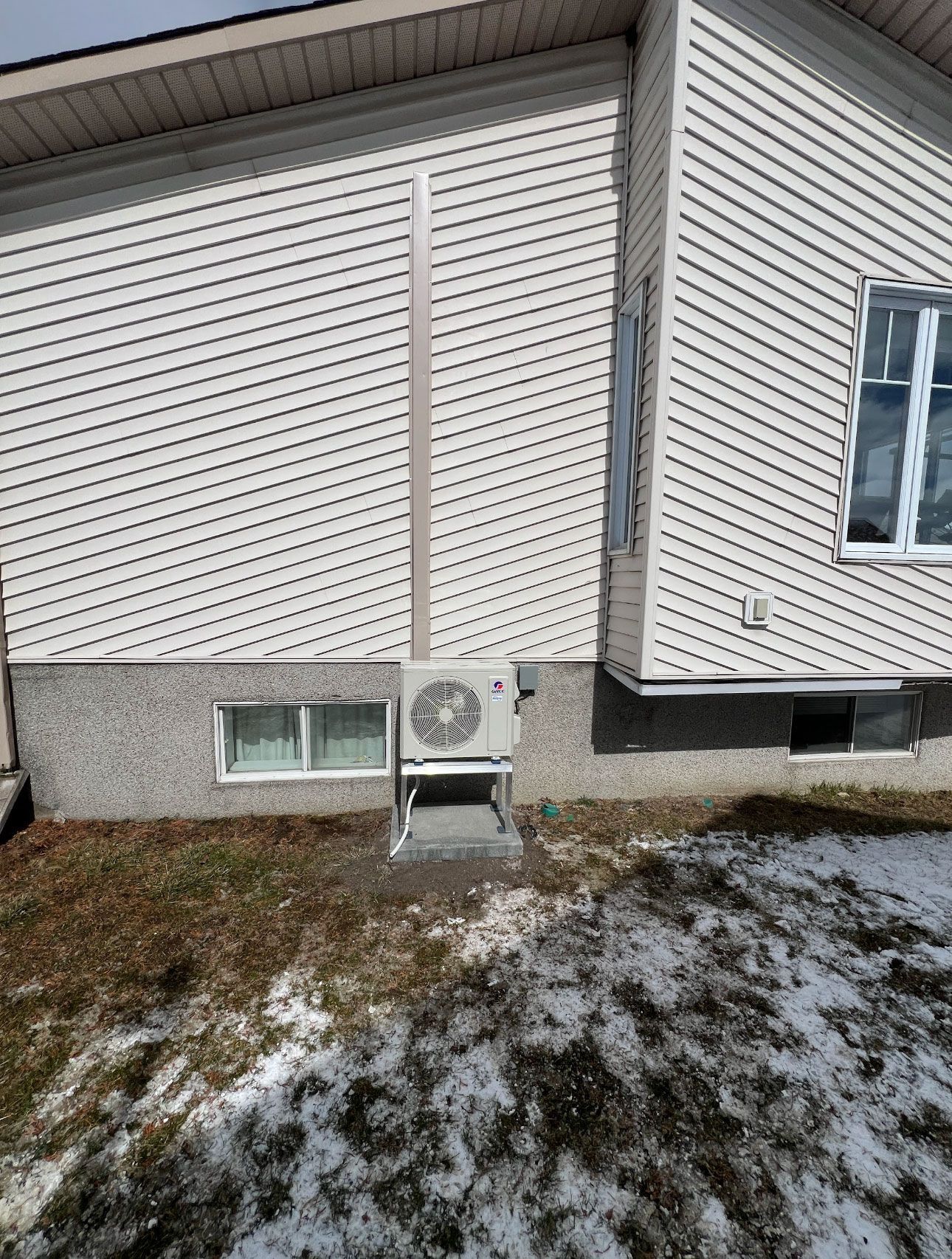 Une maison blanche avec un grand climatiseur sur le côté.