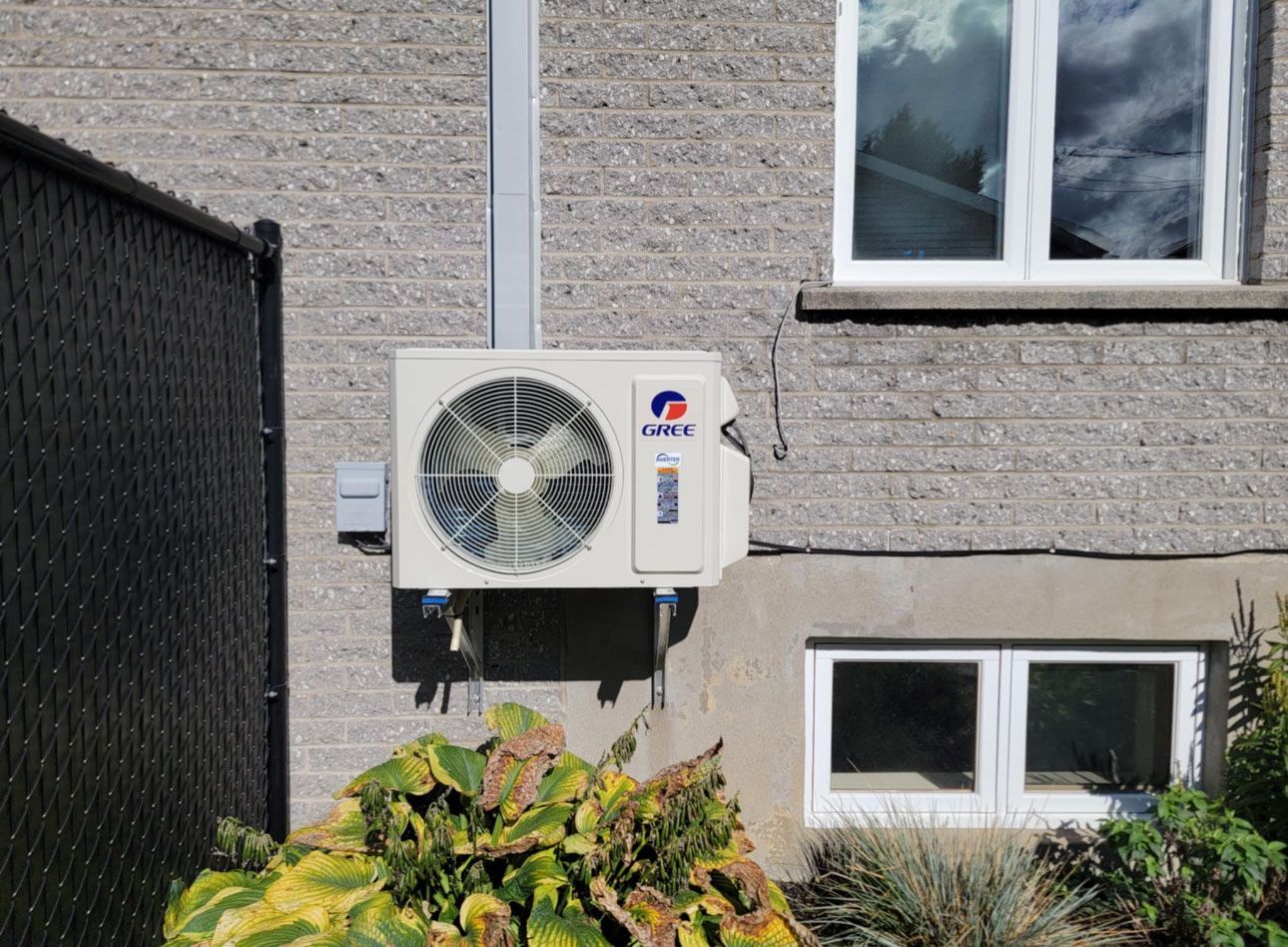 Un climatiseur blanc est monté sur le côté d'un bâtiment en briques à côté d'une fenêtre.