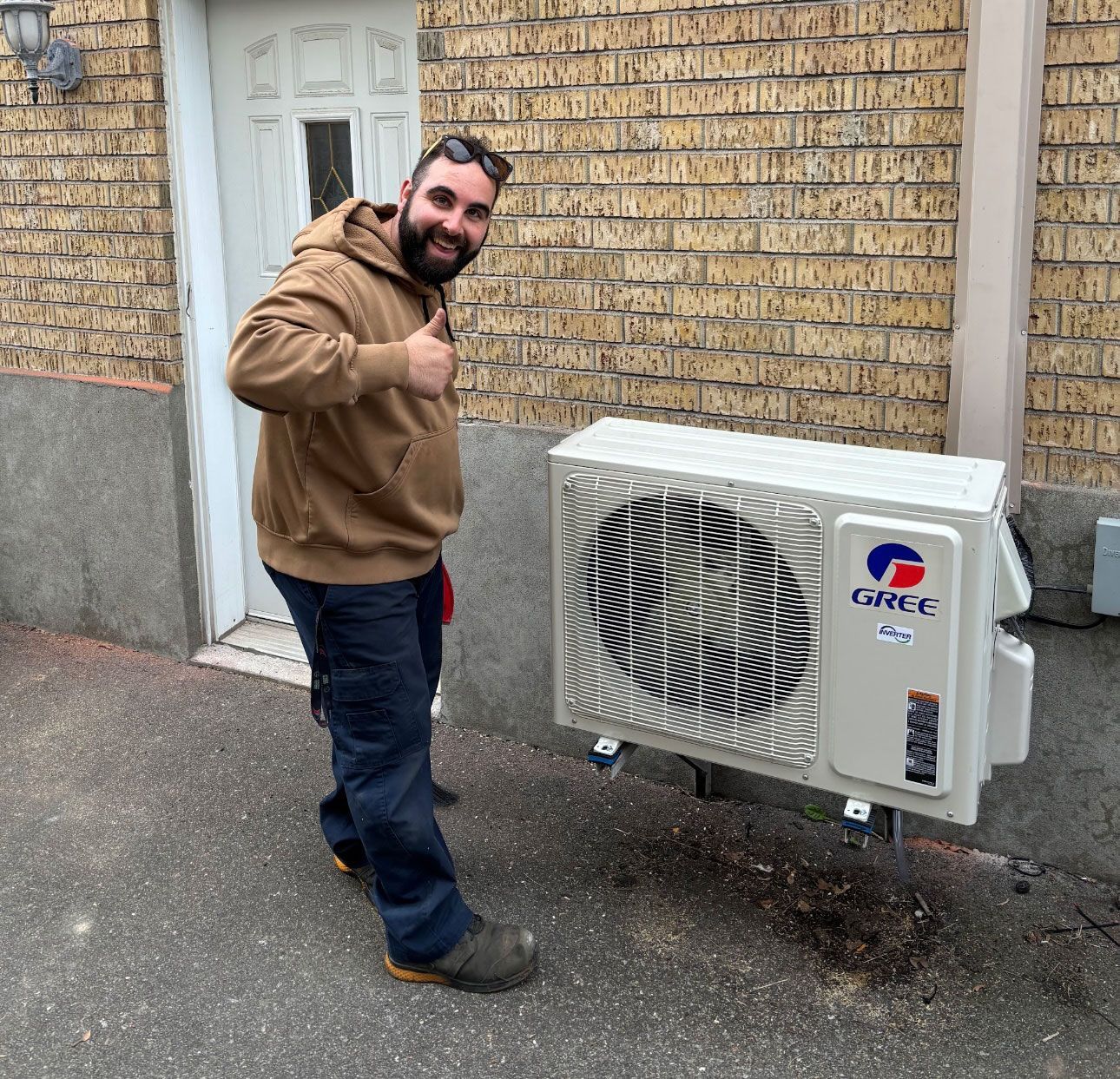 Un homme lève le pouce à côté d'un climatiseur gree.