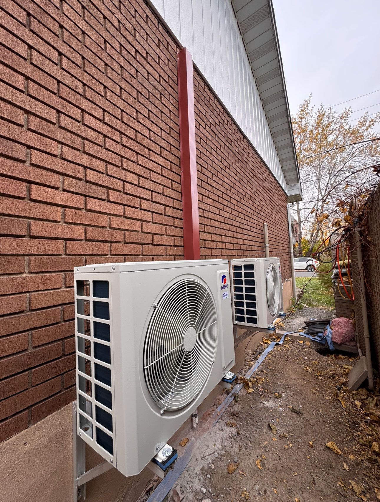 Deux climatiseurs sont installés sur le côté d'un bâtiment en briques.