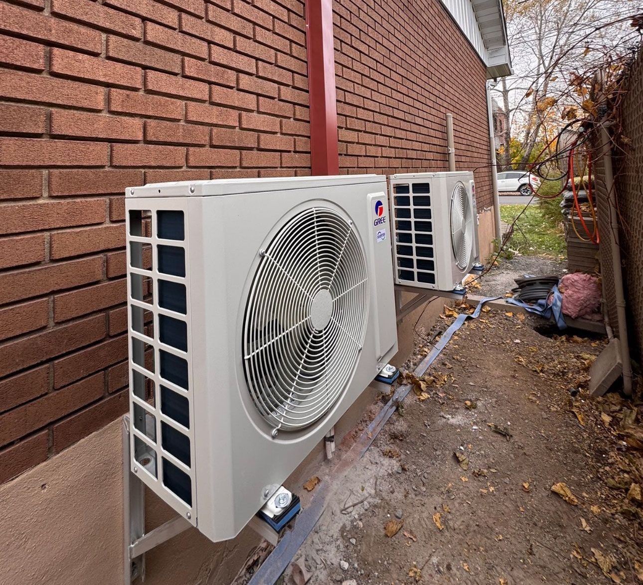 Deux climatiseurs sont montés sur le côté d'un bâtiment en briques.