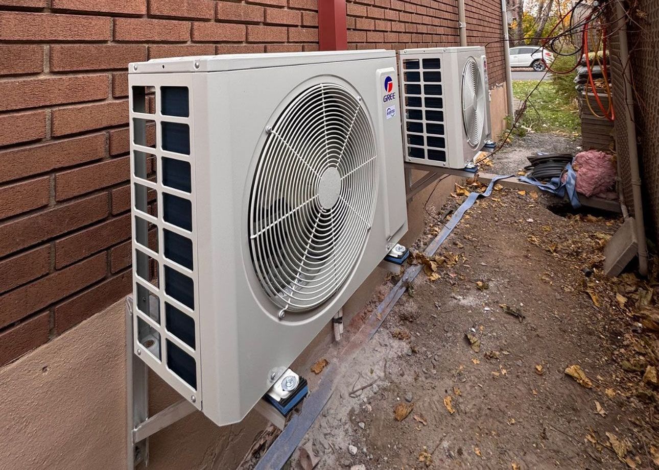 Deux climatiseurs sont montés sur le côté d'un mur de briques.