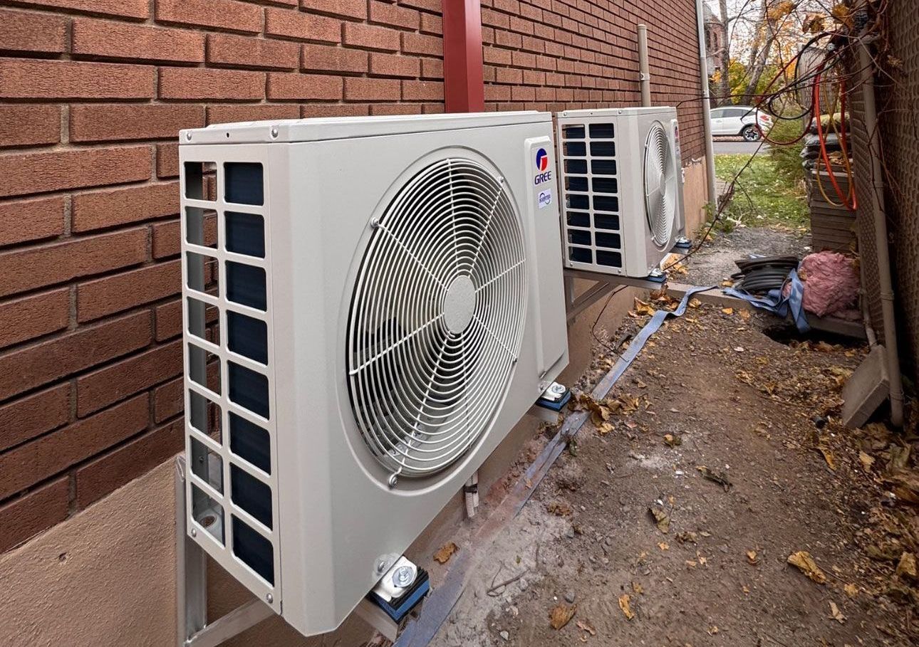 Deux climatiseurs sont posés sur le côté d'un bâtiment en briques.