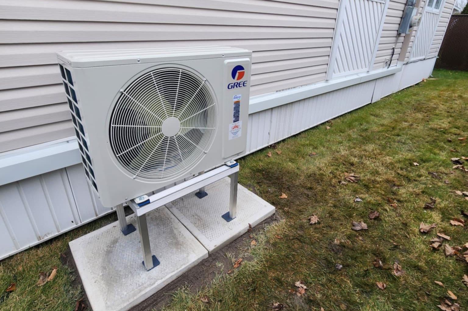 Un climatiseur blanc est installé à l'extérieur d'une maison.