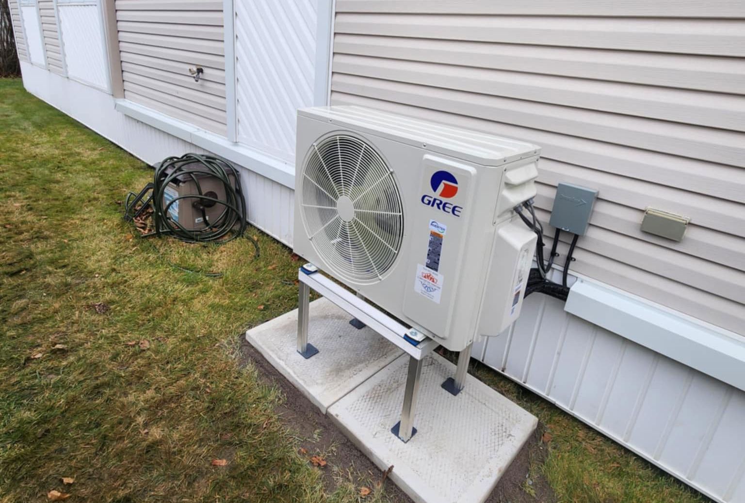 Un climatiseur gree est installé à l'extérieur d'une maison.