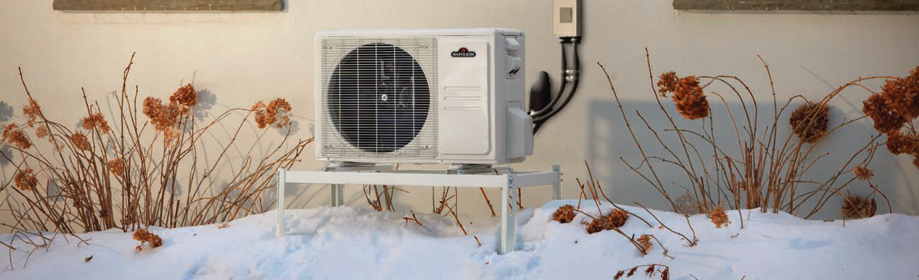 Un climatiseur blanc est posé dans la neige sur le côté d'un bâtiment.