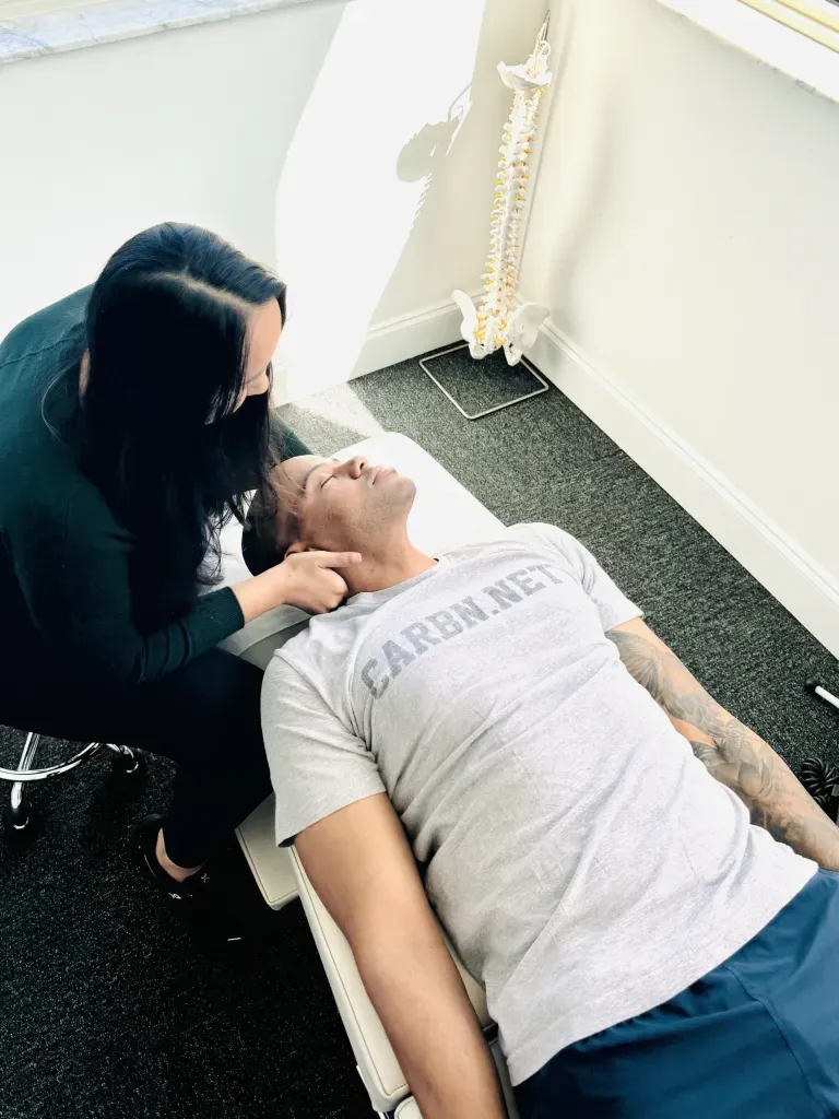 Person leaning over and checking another person lying on a treatment table in a bright room