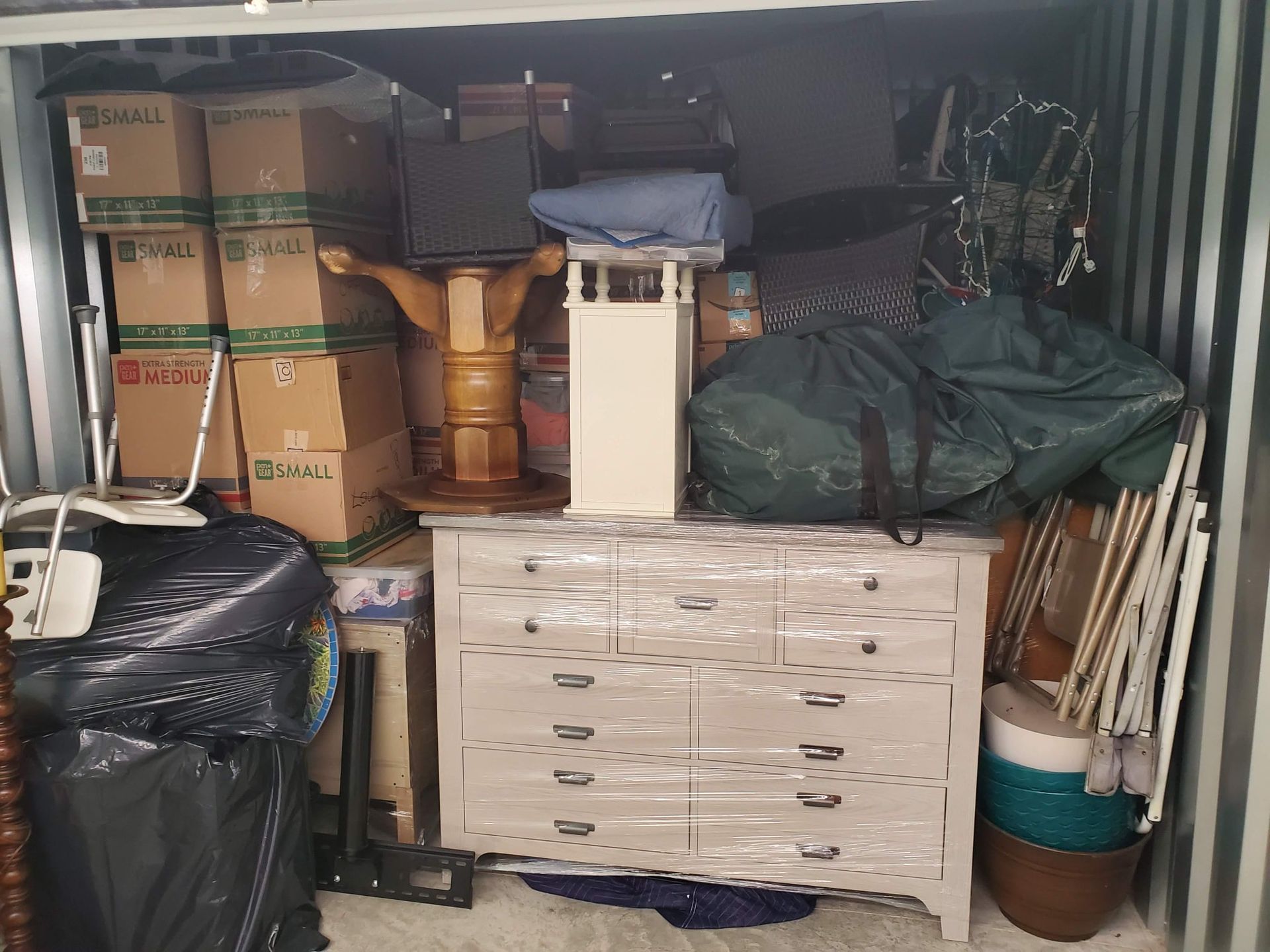A storage container filled with boxes , a dresser , and other items.