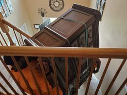 A man is carrying a dresser up a set of stairs.