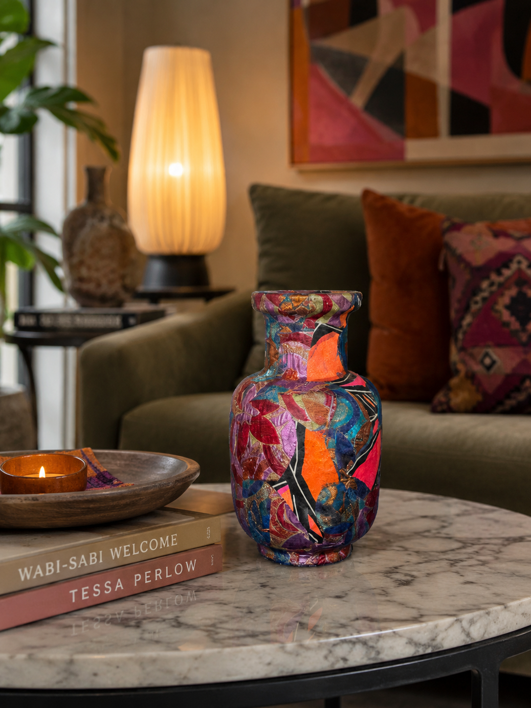 Een kleurrijke vaas met patroon op een marmeren salontafel in een gezellige woonkamer met een lamp en kussens.