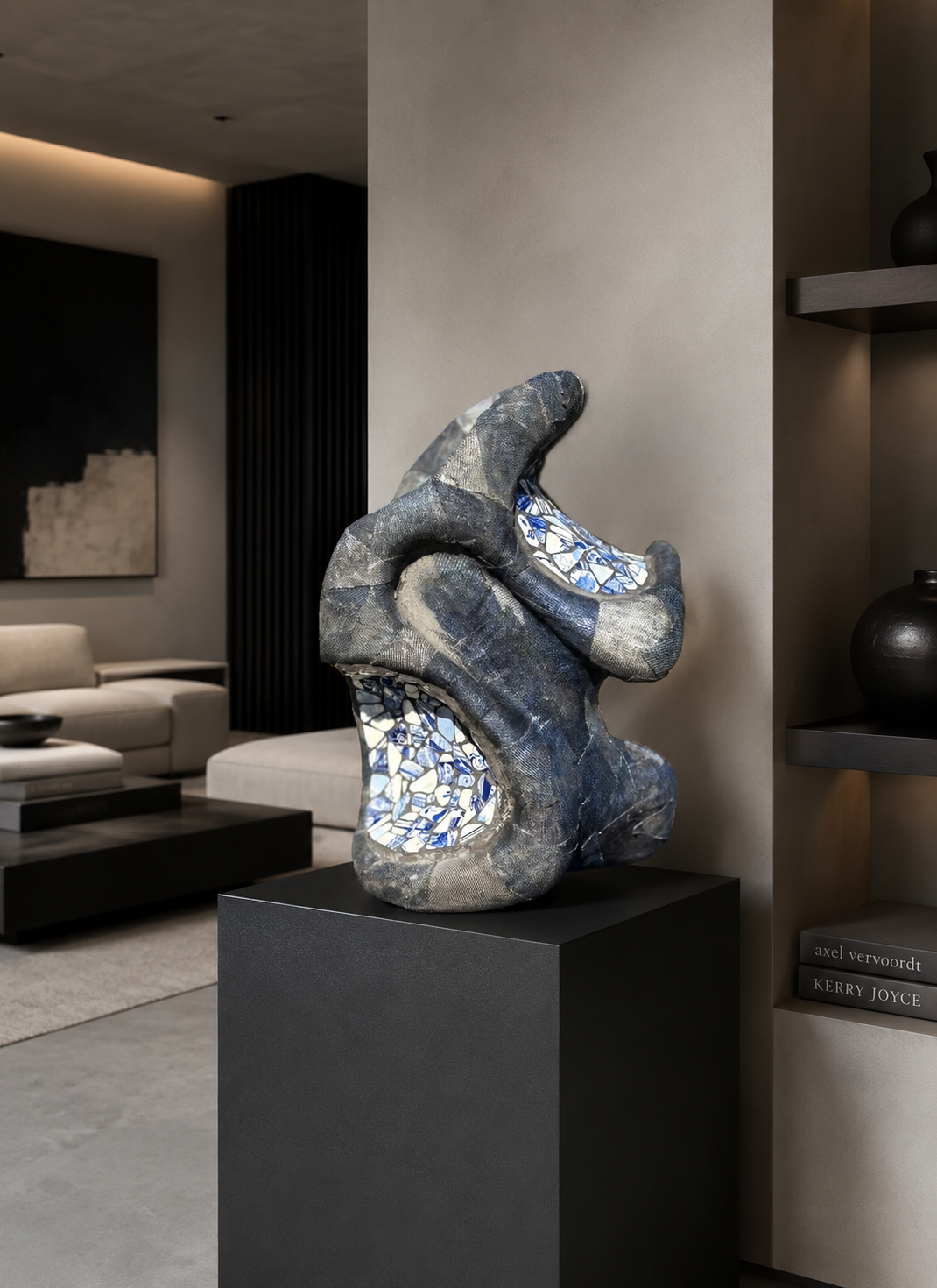 Abstracte zilver-blauwe sculptuur op een zwarte sokkel in een moderne woonkamer.