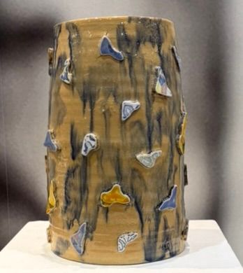 Een keramische vaas staat op een witte tafel.