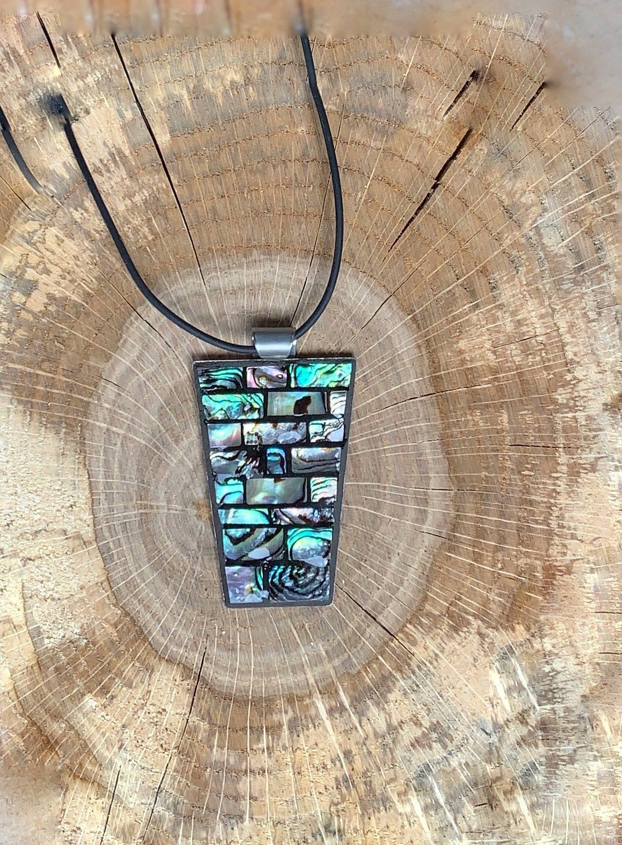 Een close-up van een ketting met een mozaïekhanger op een houten oppervlak.