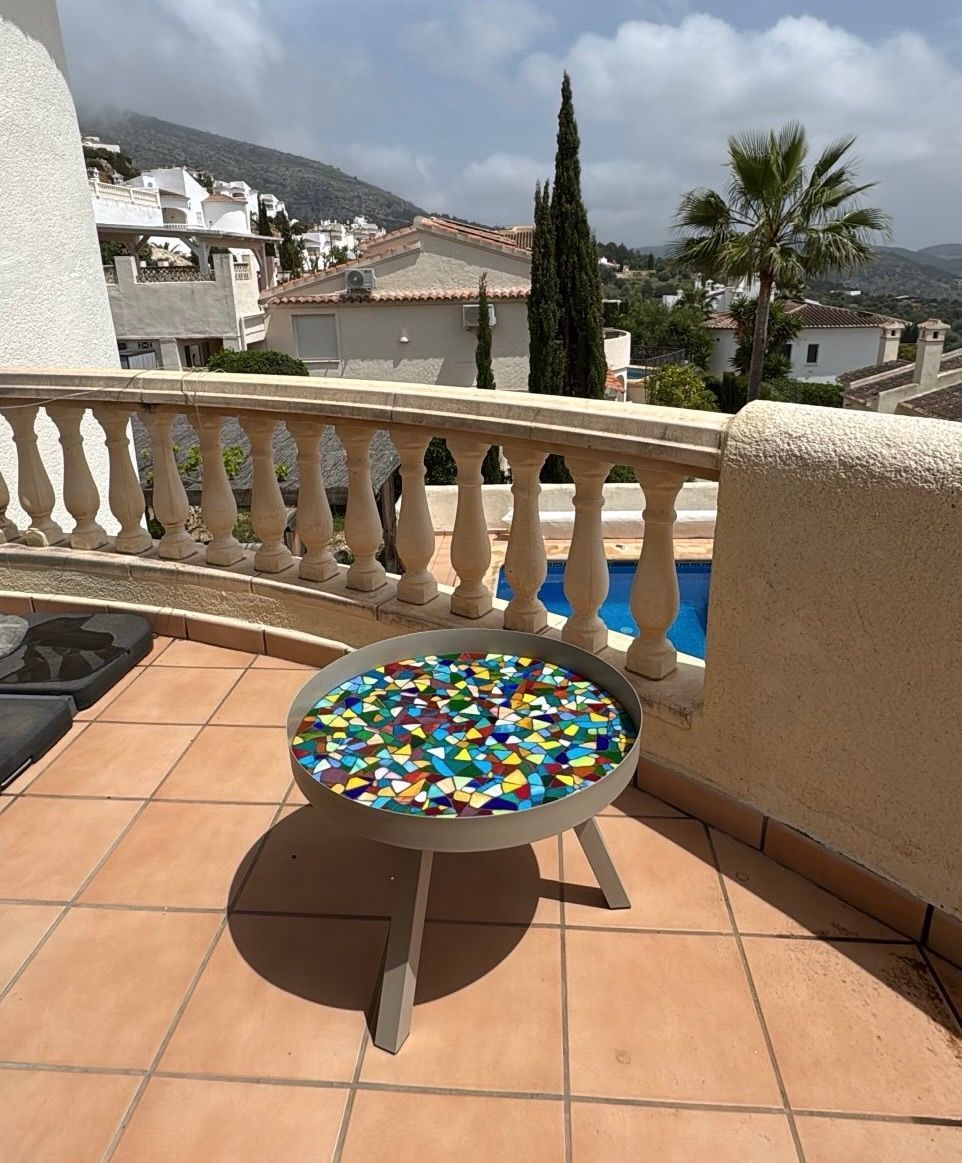 Een klein tafeltje op een balkon met uitzicht op een zwembad