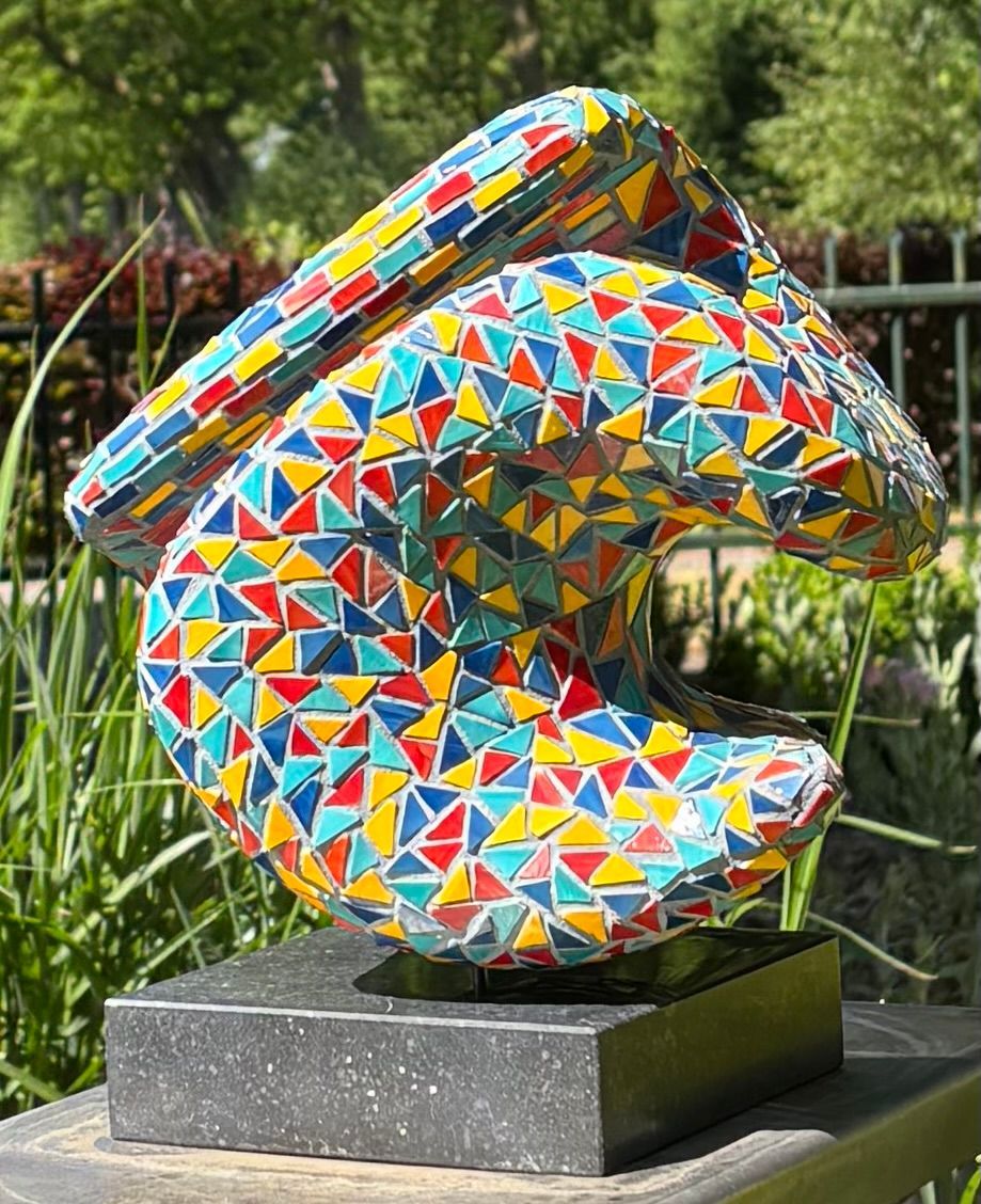 Een kleurrijk beeld staat op een zwarte sokkel