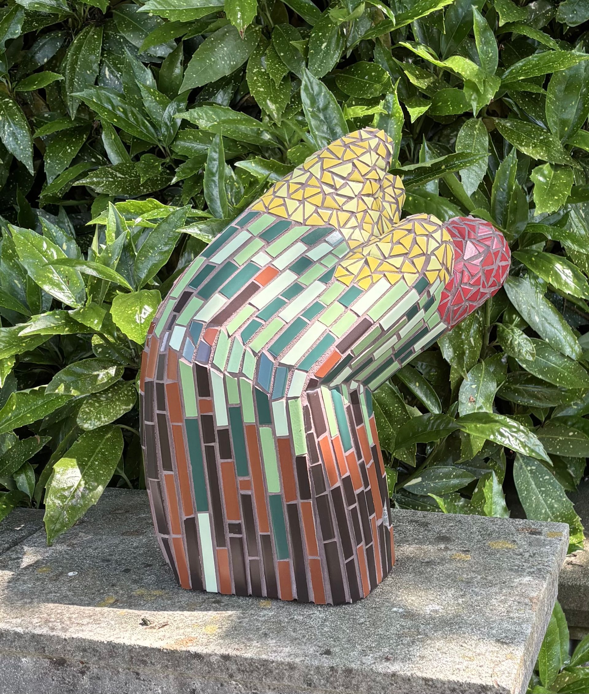 Een mozaïeksculptuur van een hand met een rood hart