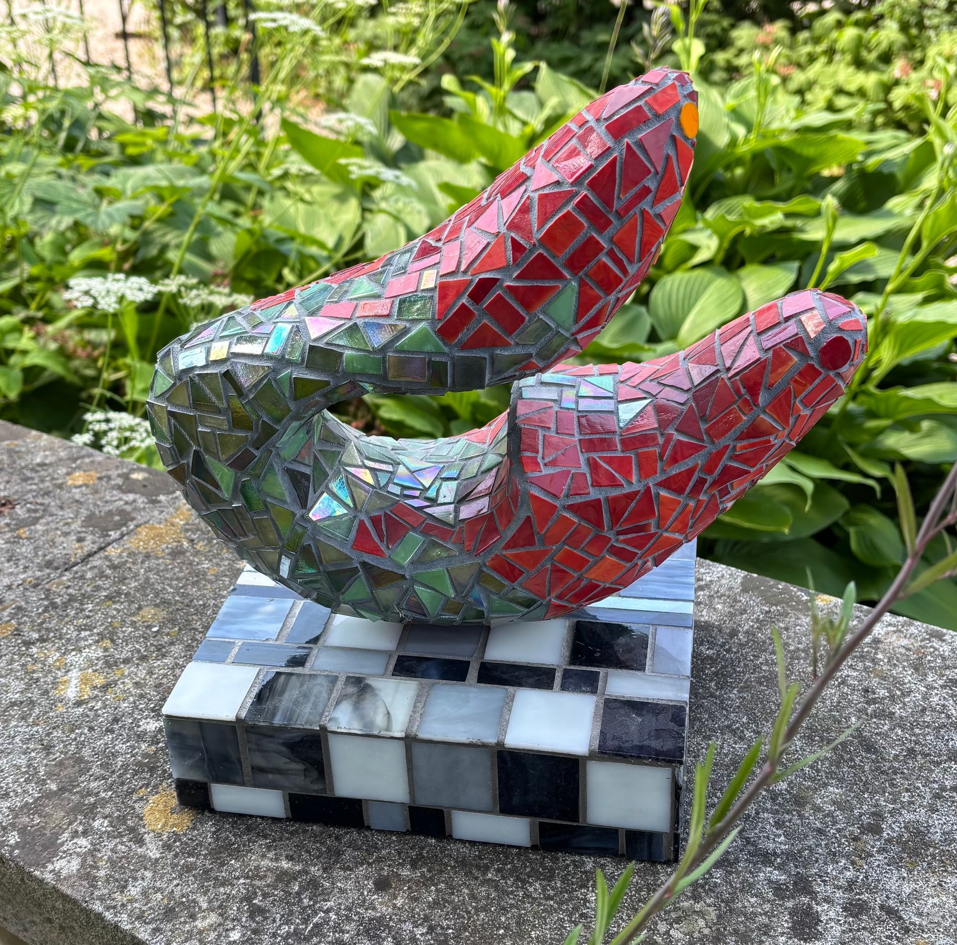 Een mozaïekbeeldhouwwerk staat op een zwarte sokkel