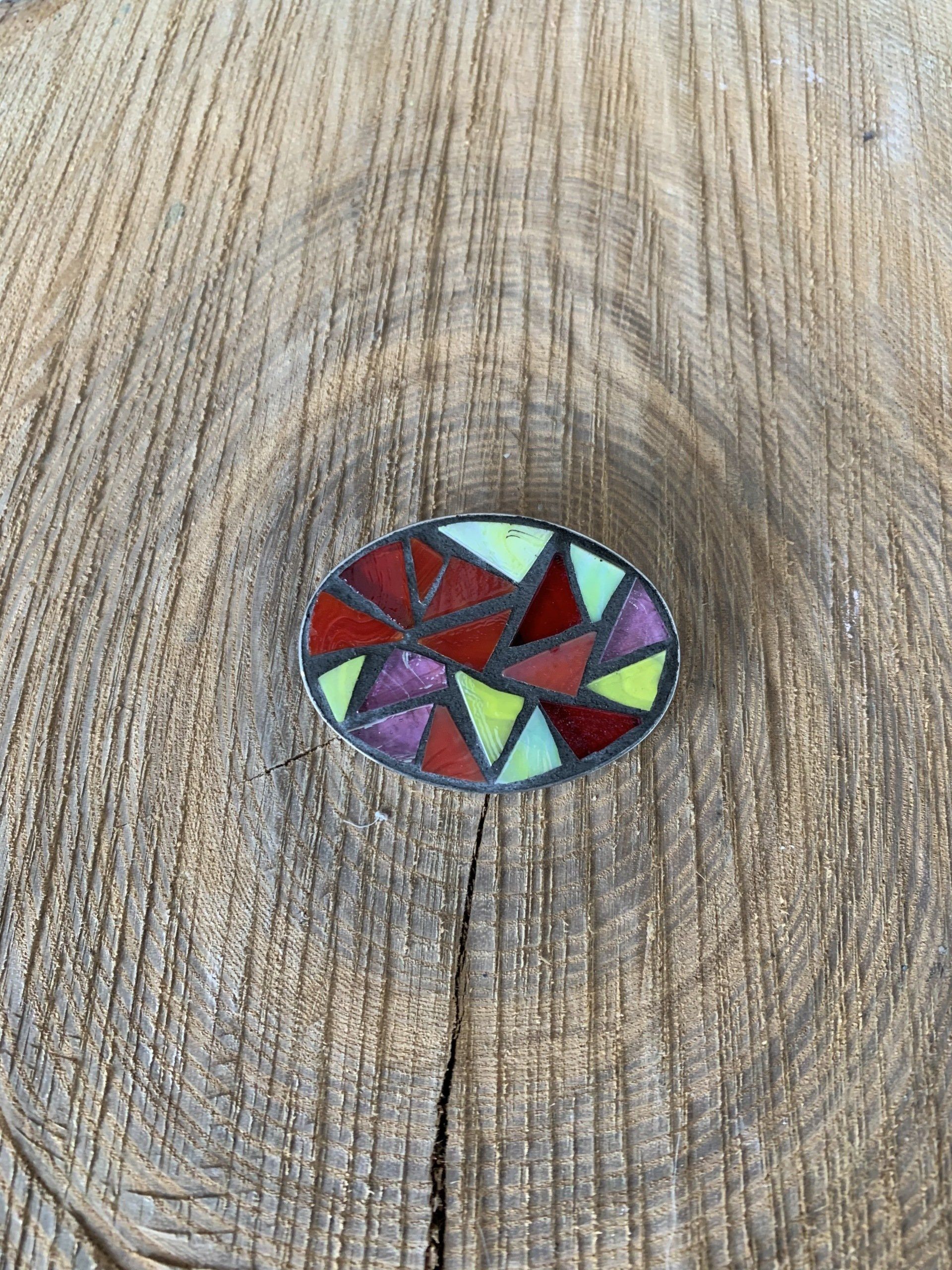 Een close-up van een broche met een mozaïekhanger op een houten oppervlak.