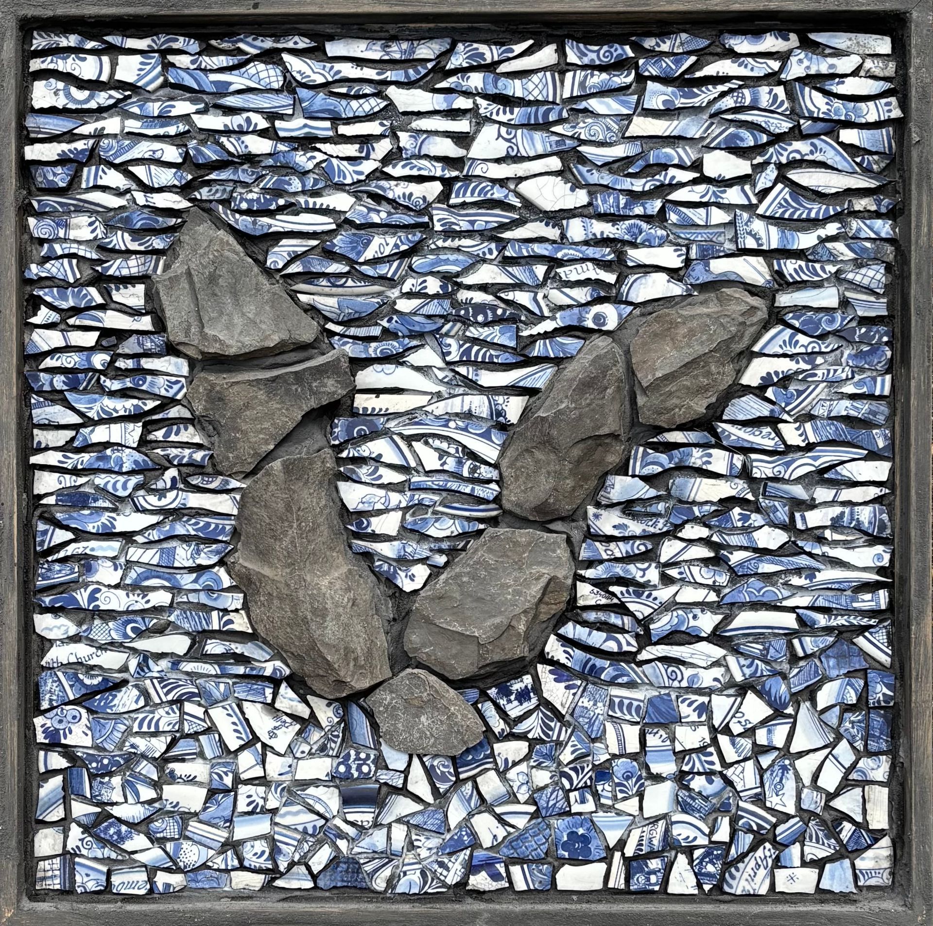 Een mozaïek van leisteen op een blauw-witte, delfts blauwe  achtergrond.