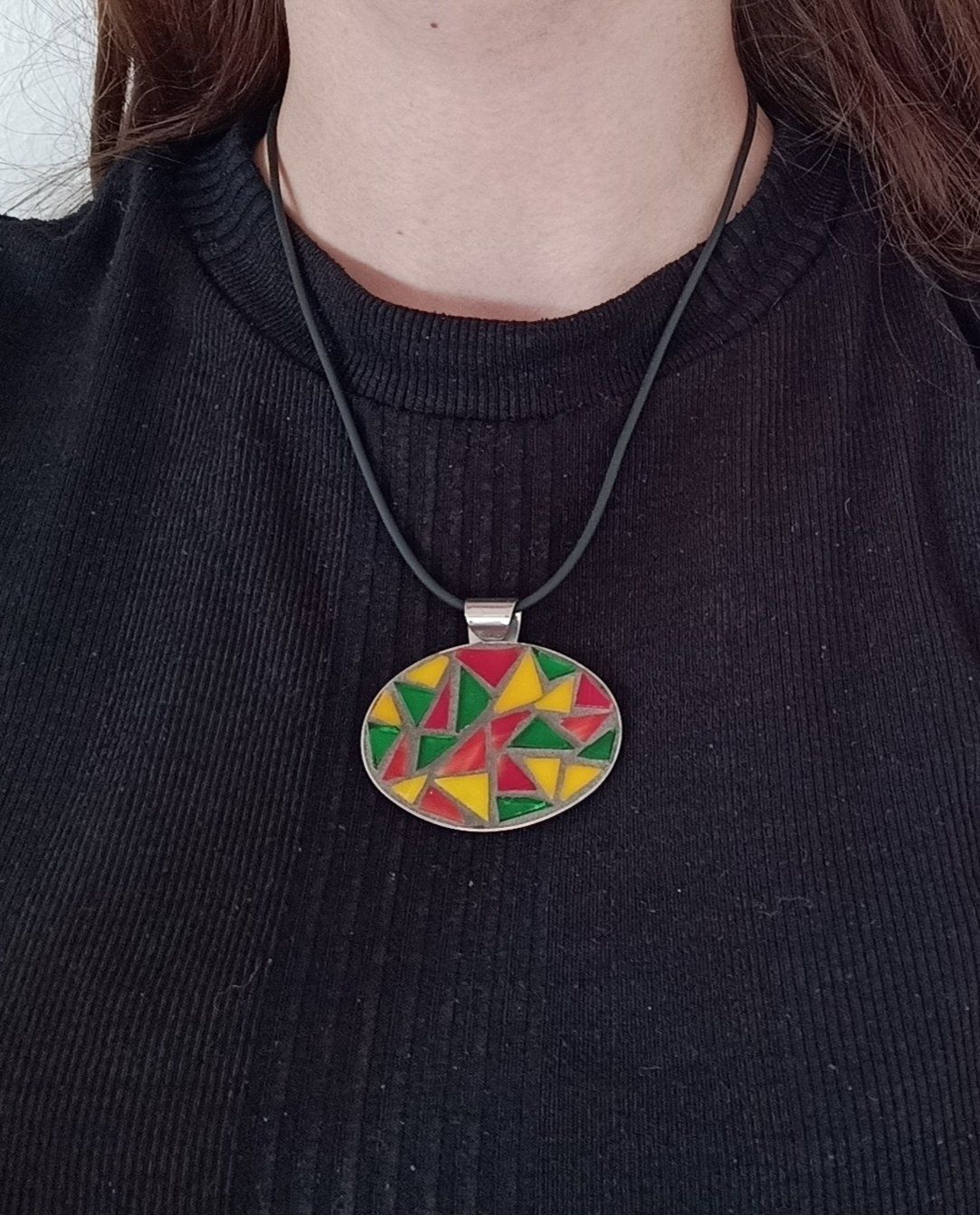 Een vrouw in een zwart shirt en een ketting met een mozaïekhanger