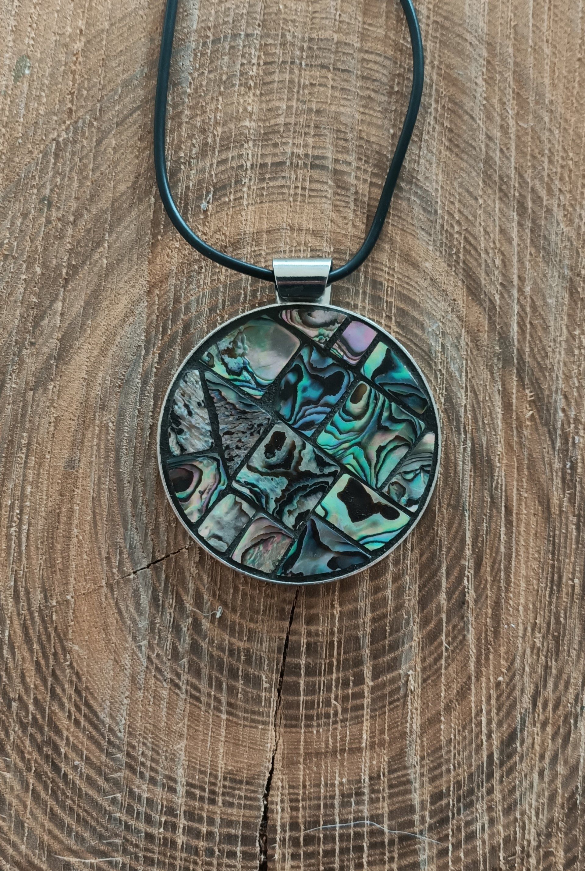 Een close-up van een ketting met een regenboogmozaïekhanger op een houten oppervlak.