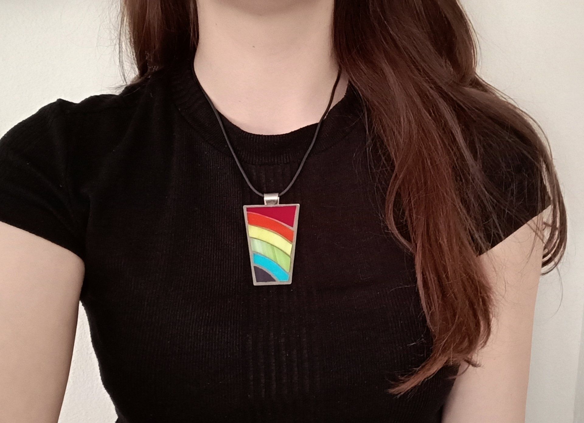 Een vrouw in een zwart shirt en een ketting met een mozaïekhanger
