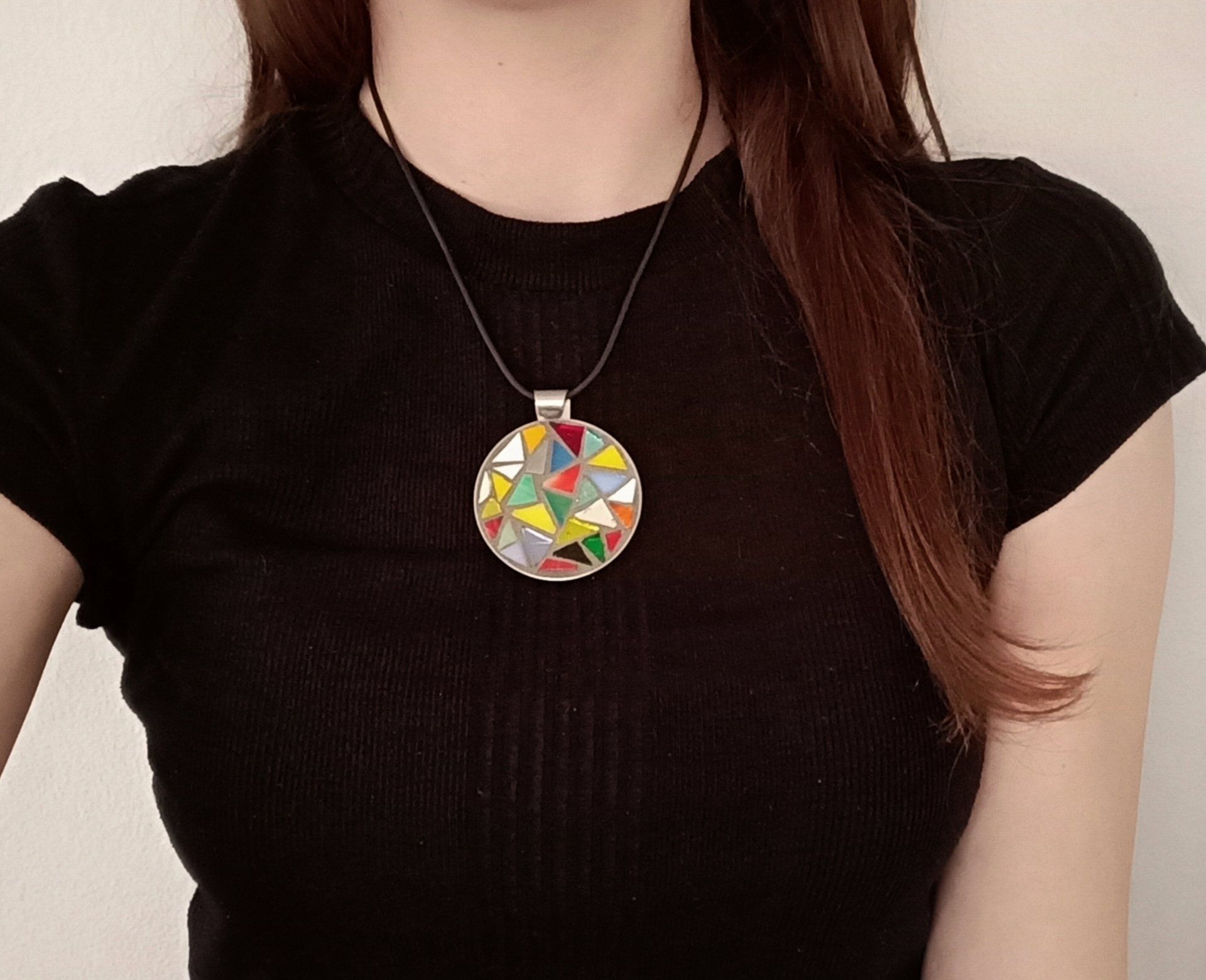 Een vrouw in een zwart shirt en een ketting met een mozaïekhanger