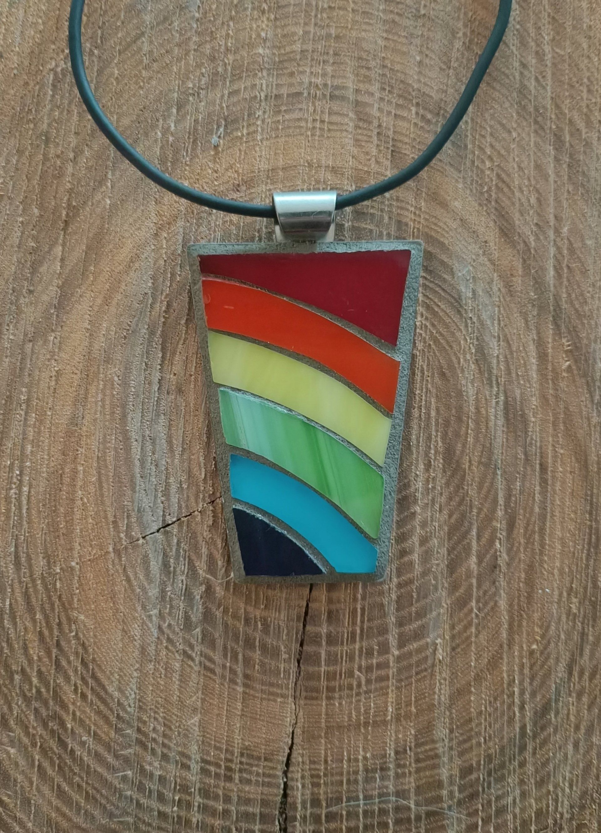 Een close-up van een ketting met een mkzaïekhanger op een houten oppervlak.