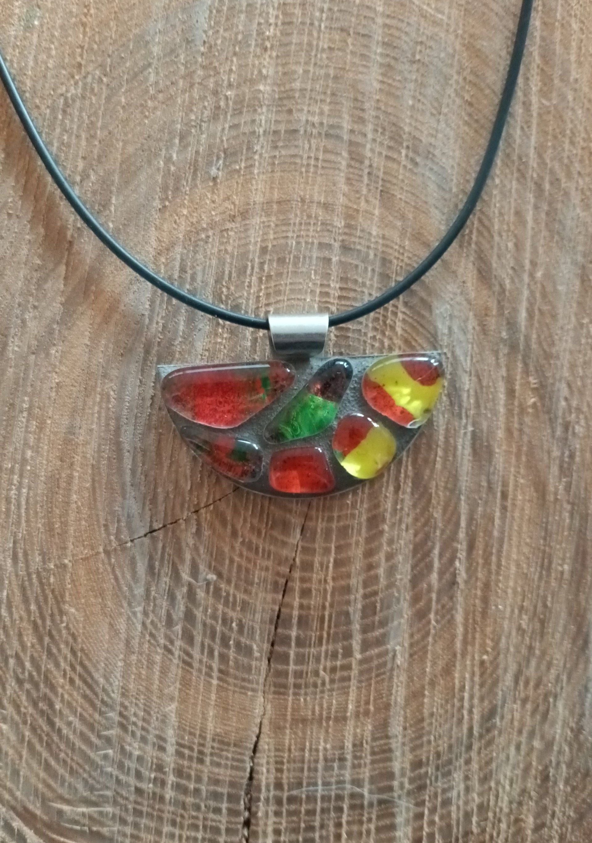 Een close-up van een ketting met een mozaïekhanger op een houten oppervlak.