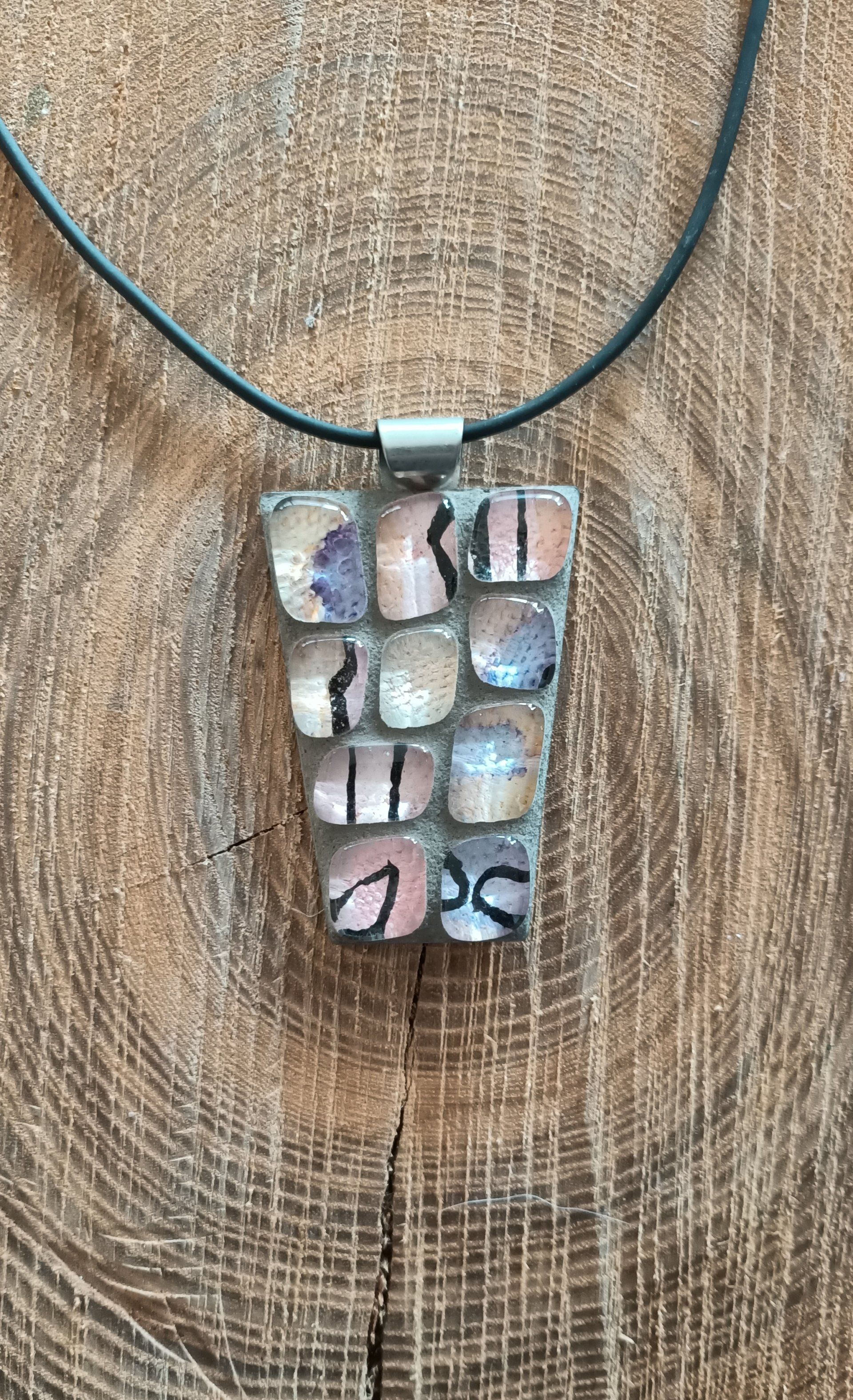 Een close-up van een ketting met een mozaïekhanger op een houten oppervlak.