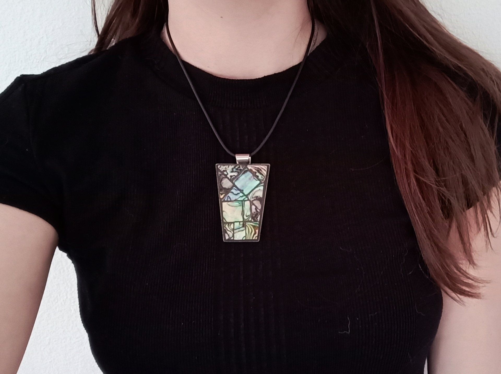 Een vrouw in een zwart shirt en een ketting met een vierkante hanger