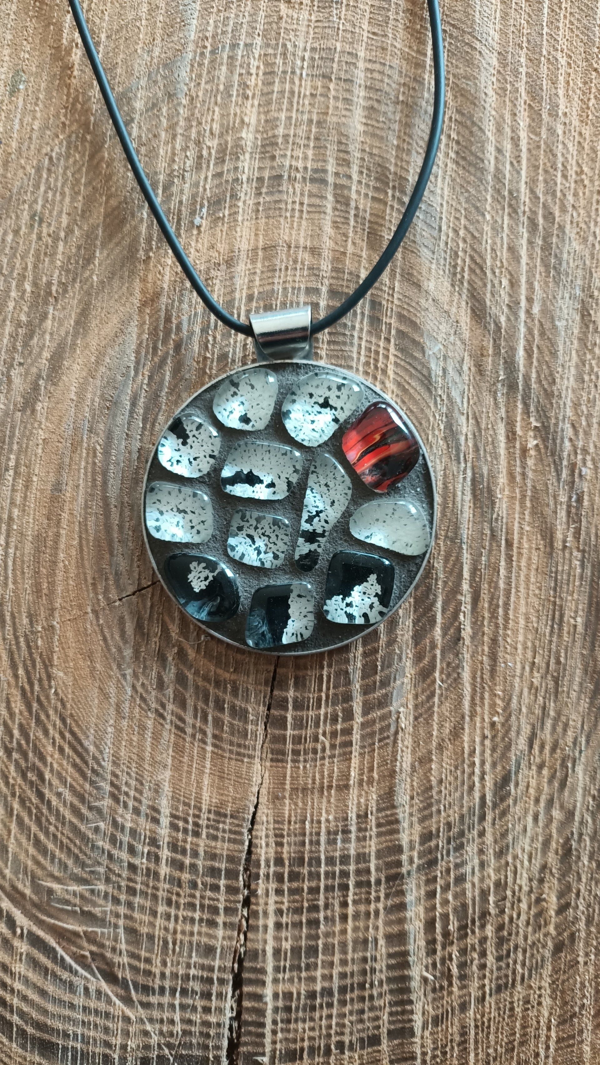 Een close-up van een ketting met een mozaïekhanger op een houten oppervlak.