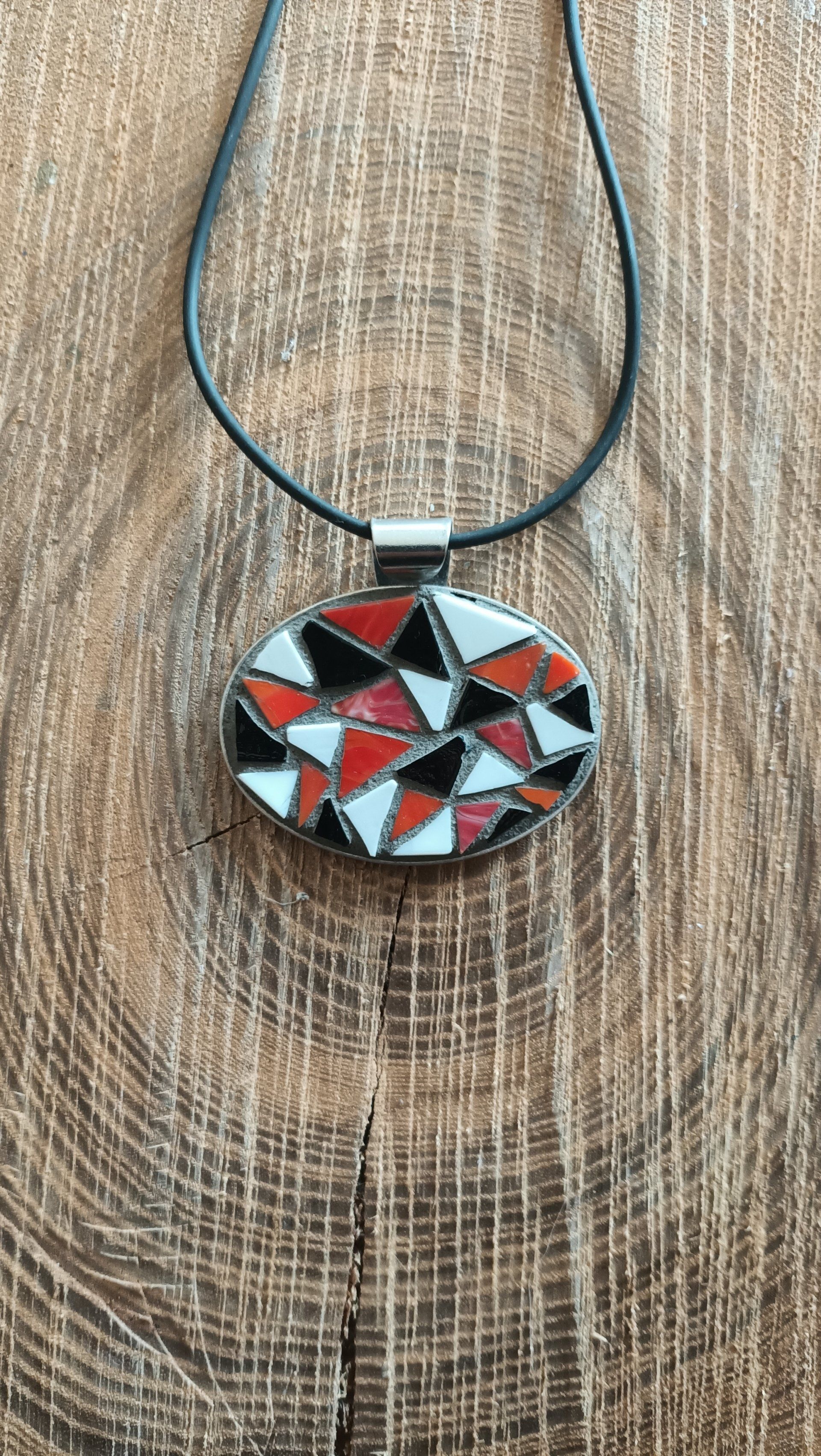 Een close-up van een ketting met een mozaïekhanger op een houten oppervlak.