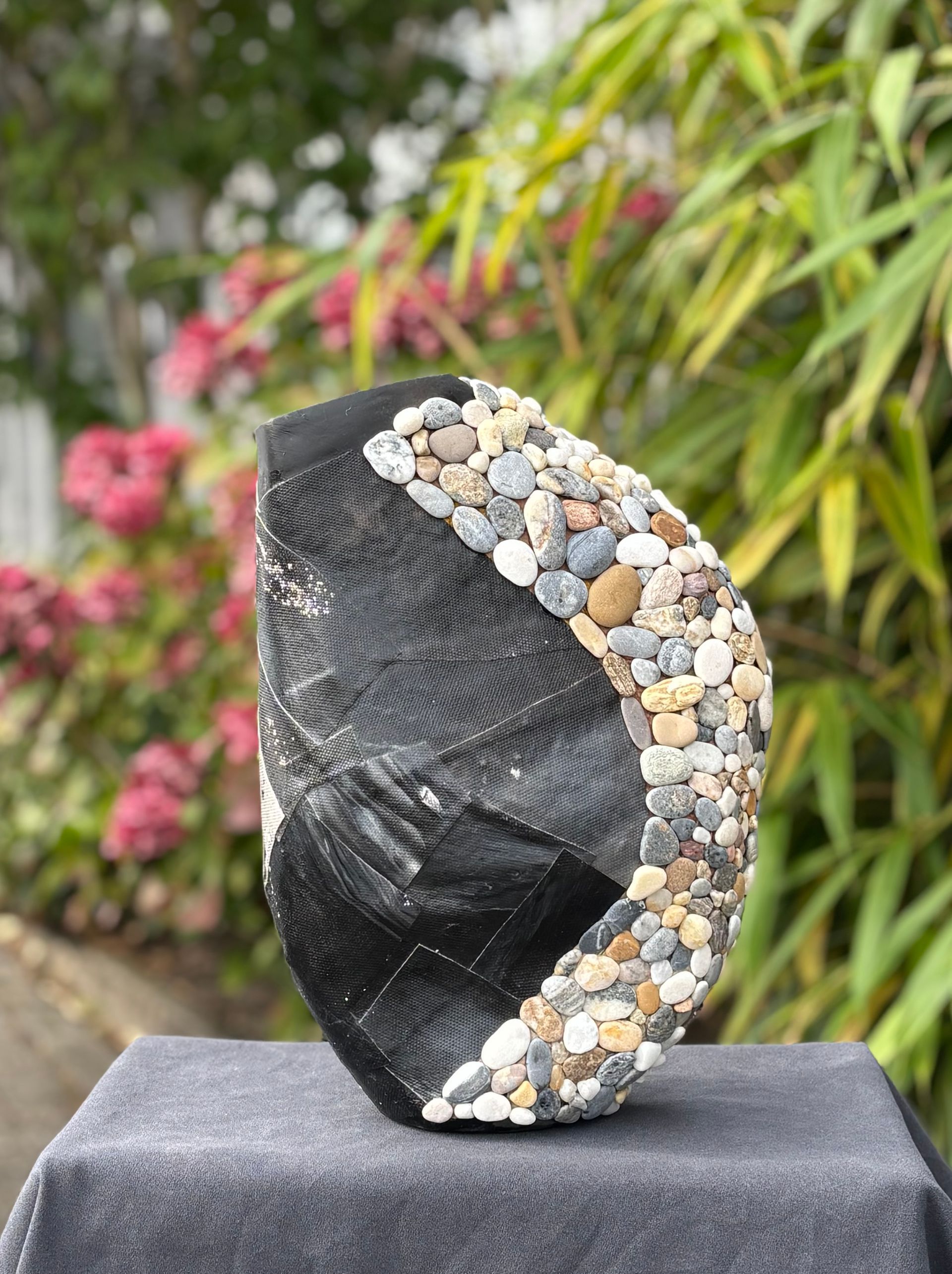 Een zwarte baseballpet van mesh met een decoratieve, gebogen strook kleine, kleurrijke rivierstenen op het zijpaneel.