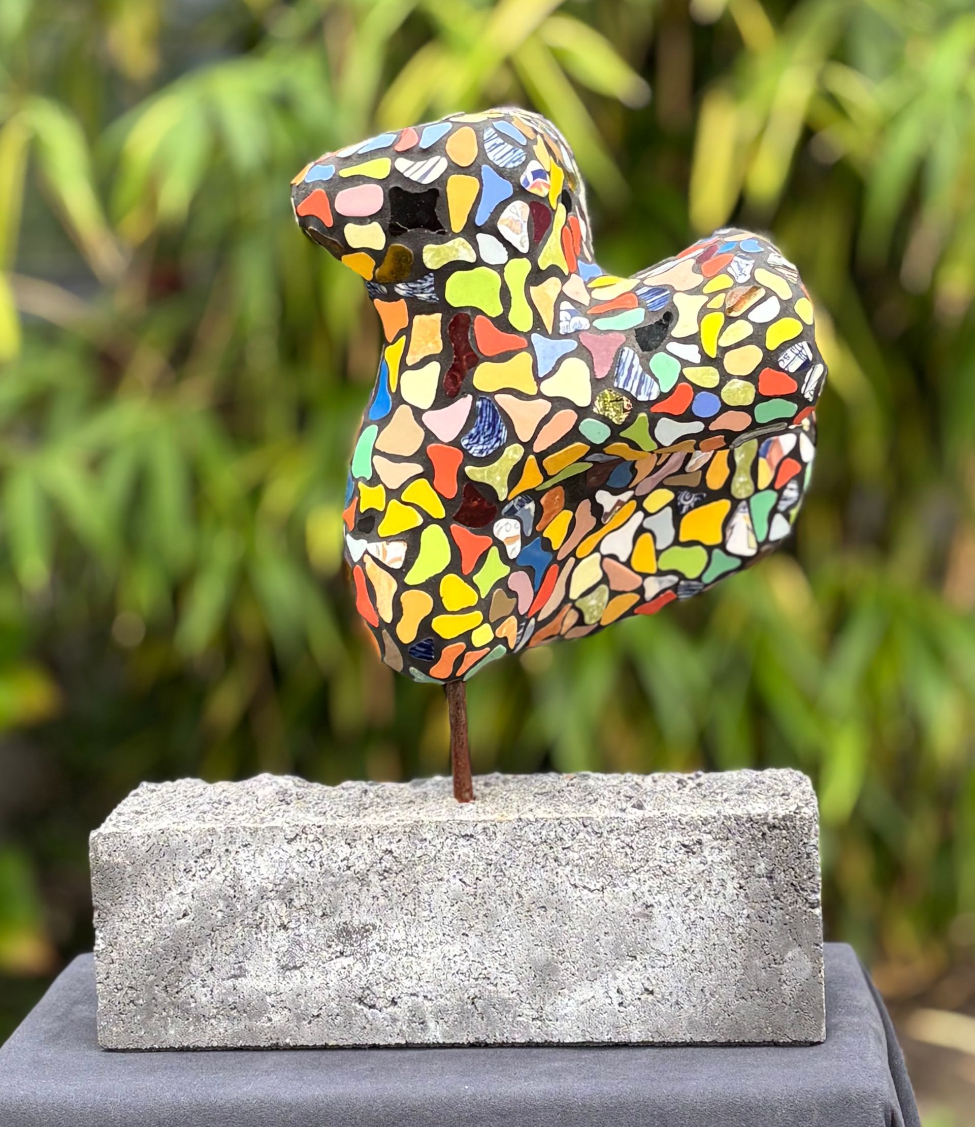 Een kleurrijk beeld staat op een betonnen voet