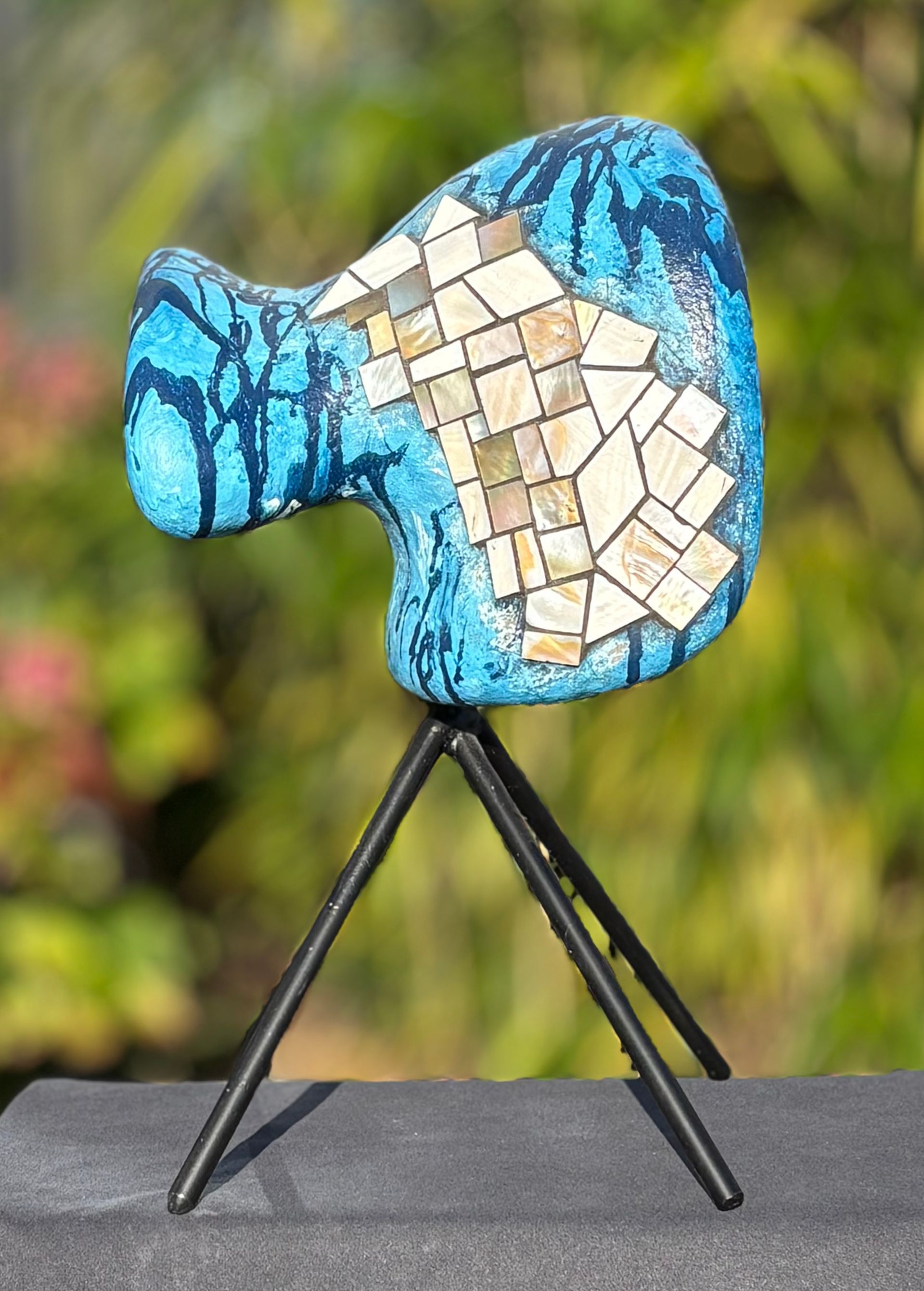 Een blauw beeld staat op een driepoot op een tafel.