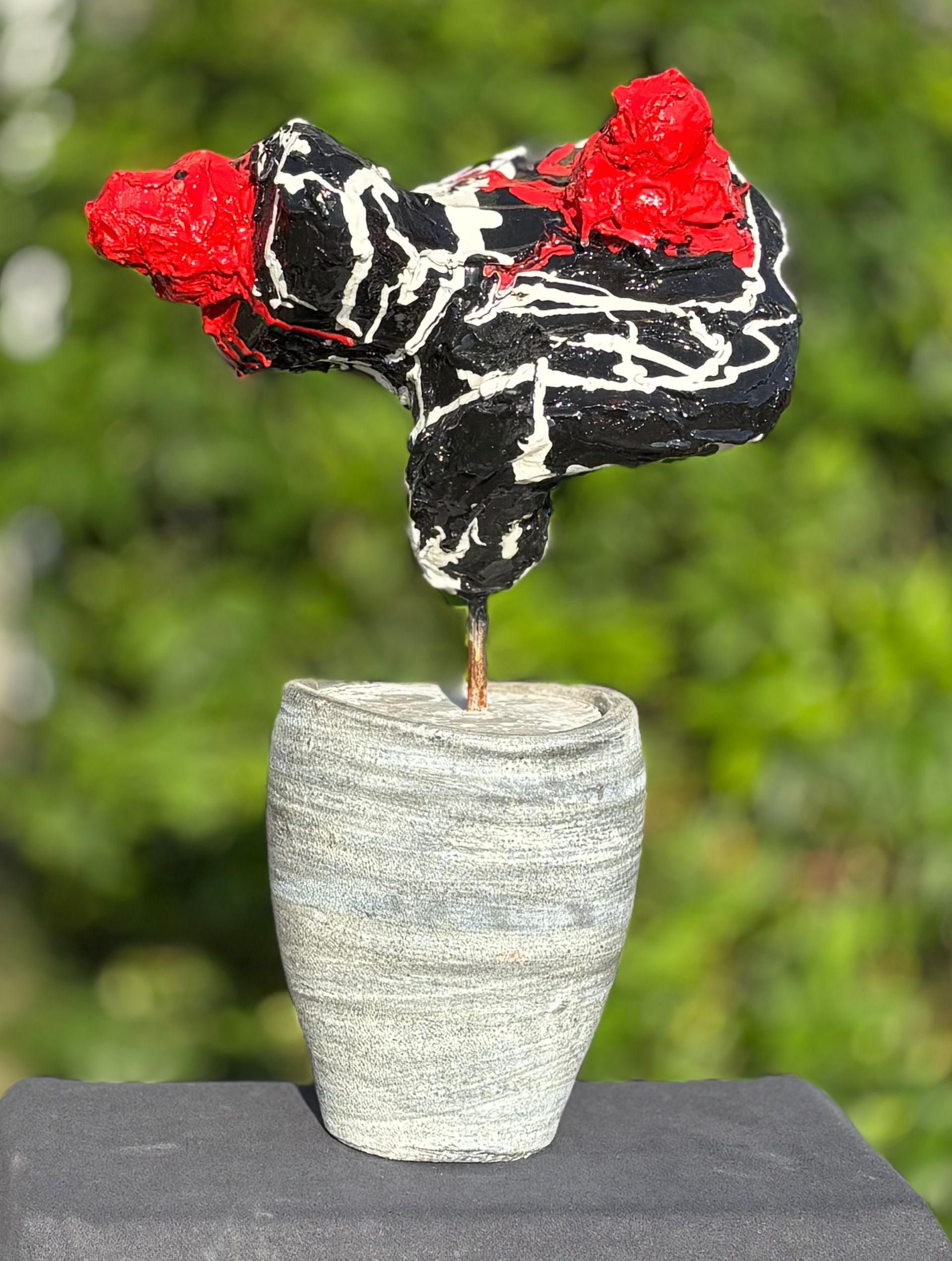 Een sculptuur van een kip in een vaas op een tafel.