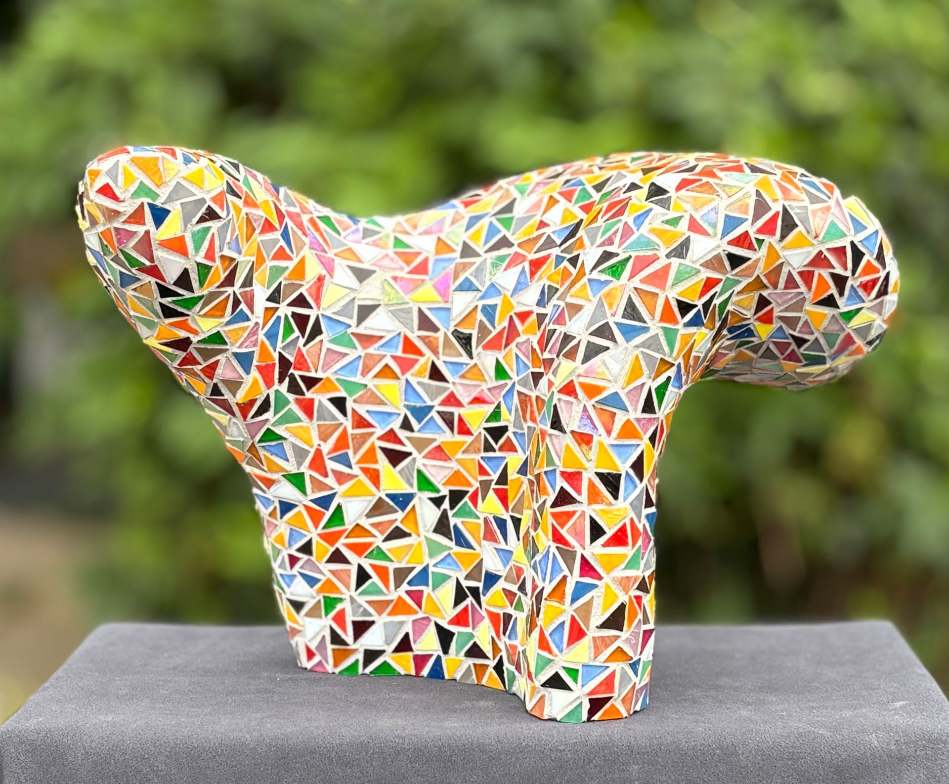 Een kleurrijk beeld staat bovenop een houten blok.