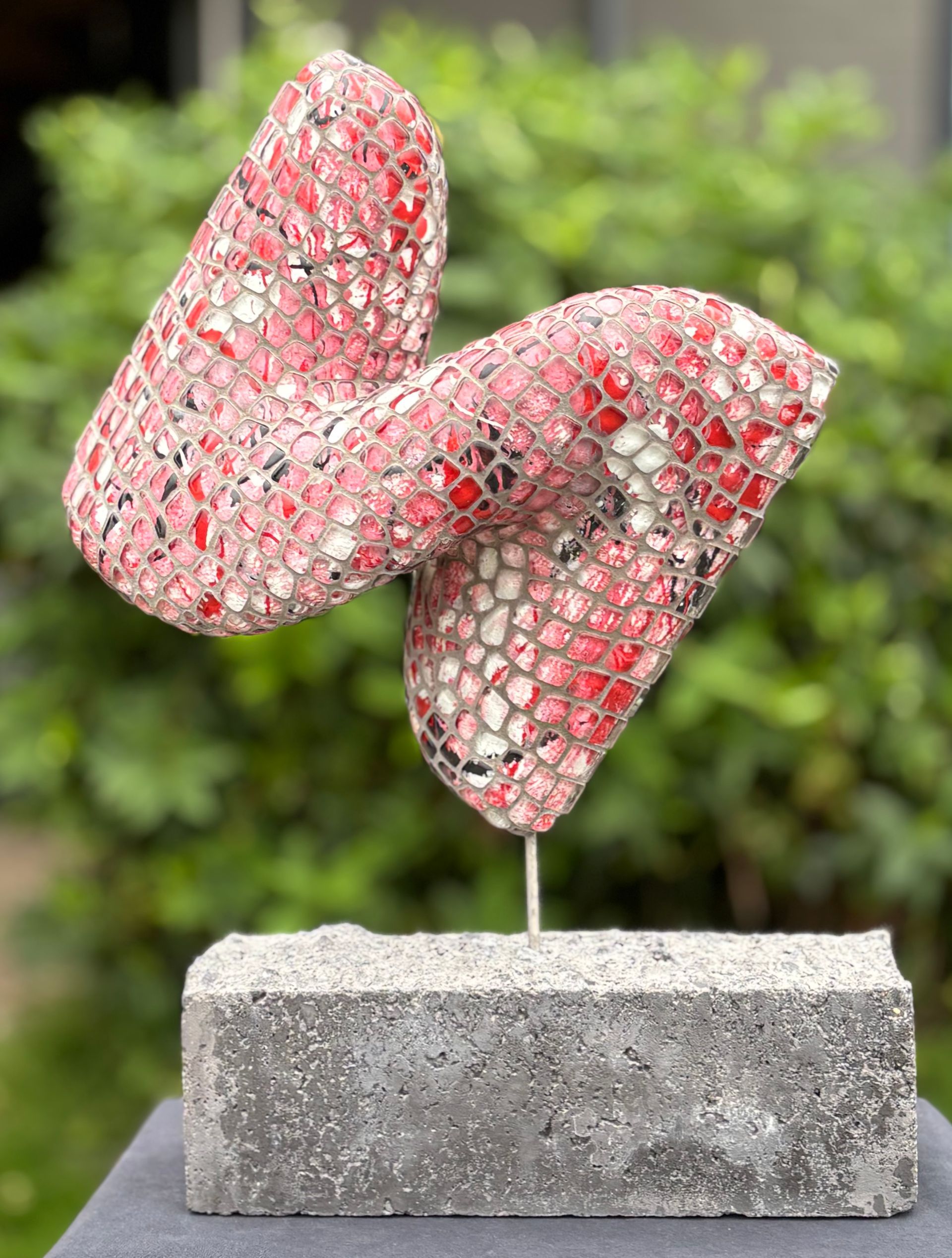 Een roze sculptuur staat bovenop een betonnen blok.