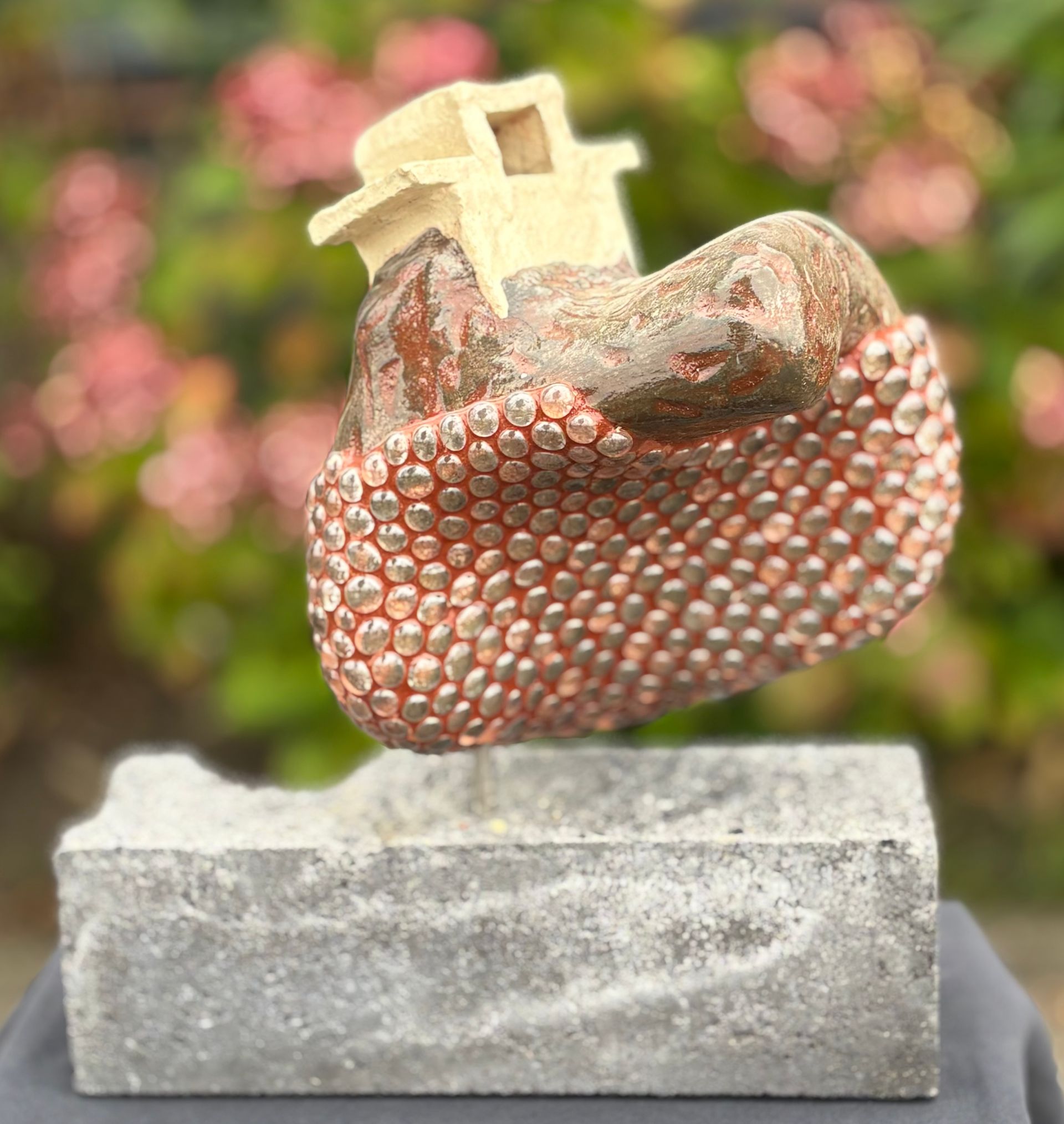 Een sculptuur met keramiek bovenop een betonnen blok.