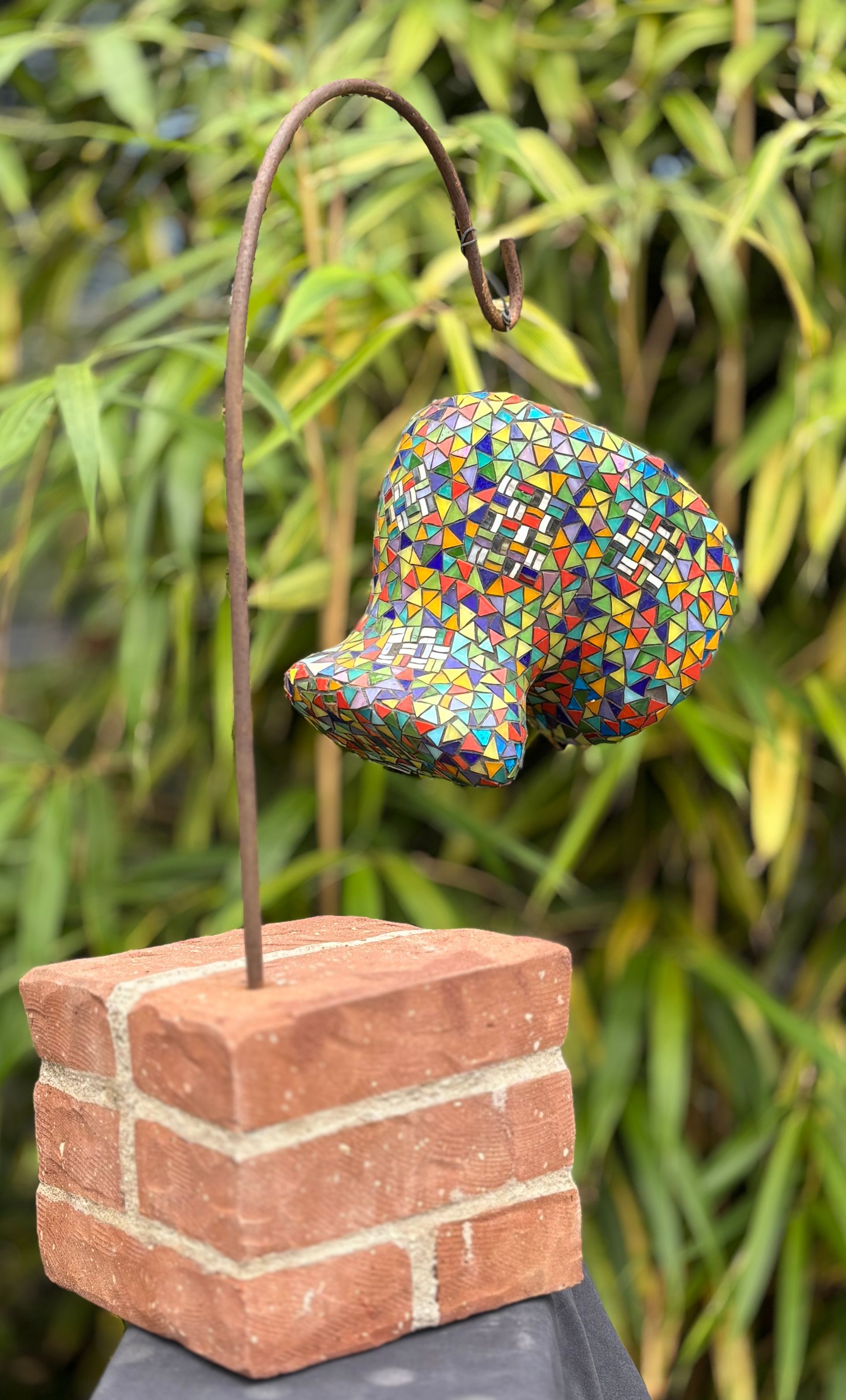 Een kleurrijk beeldhouwwerk staat op een bakstenen basis.