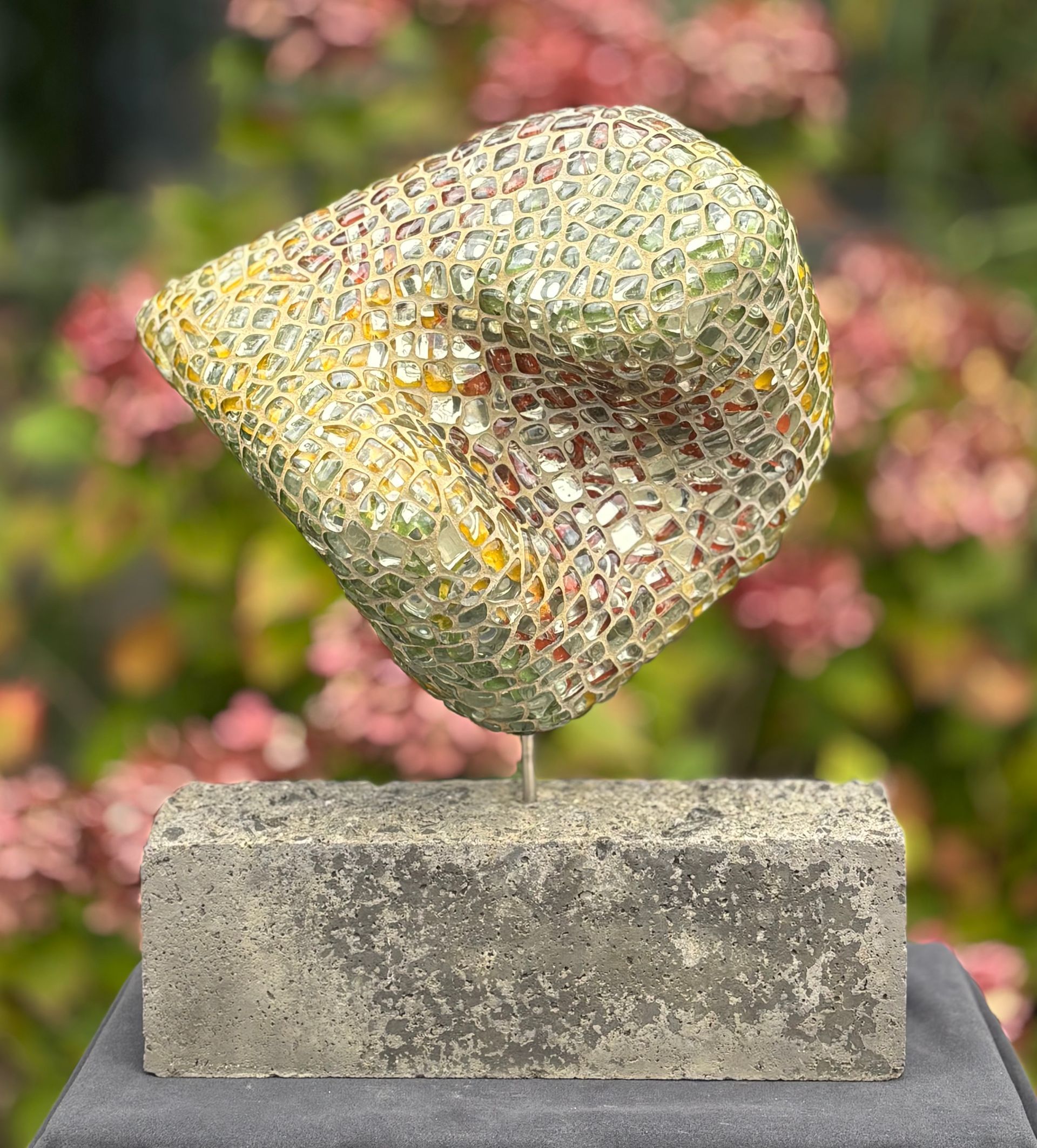 Een mozaïeksculptuur staat op een betonnen voet