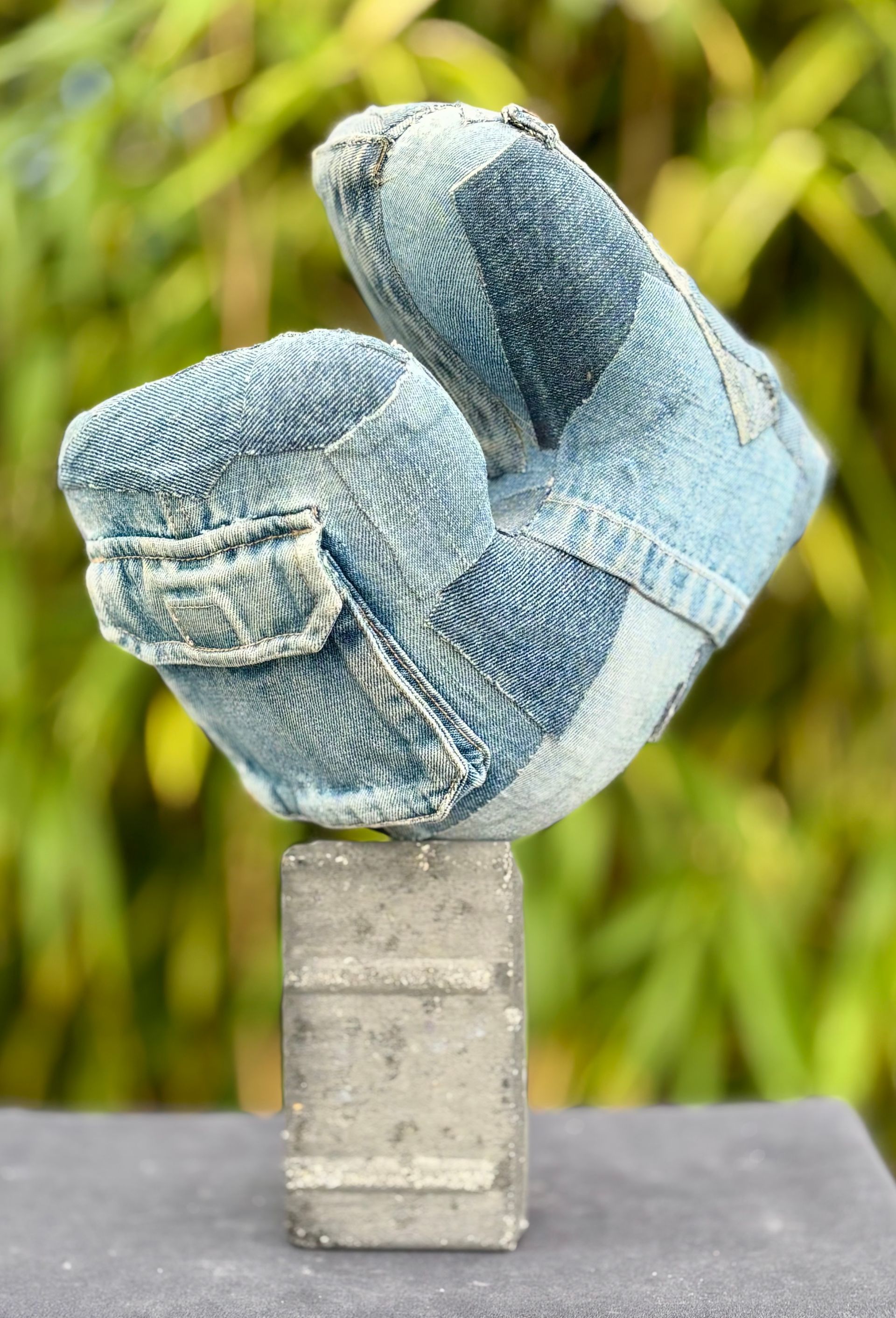 Een sculptuur van een spijkerbroek die op een betonnen blok zit.