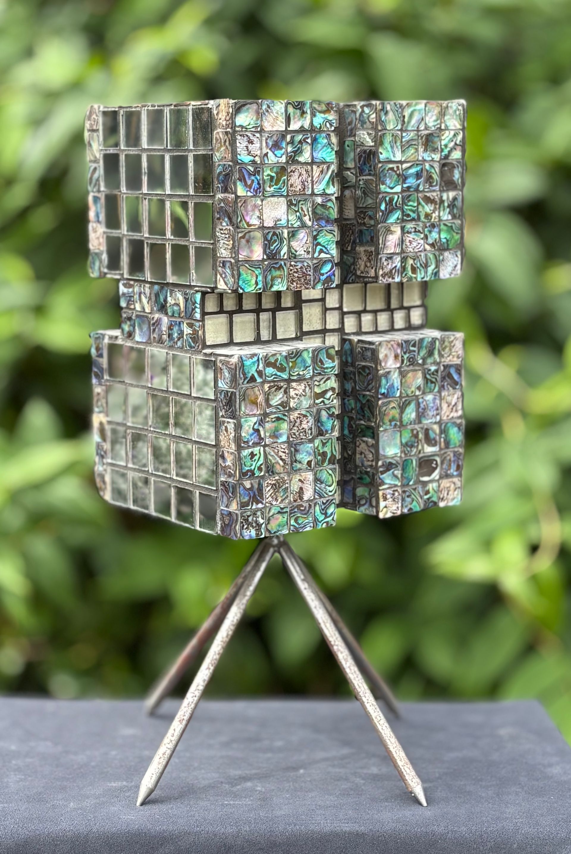 Een mozaïeksculptuur staat op een statief op een witte achtergrond.